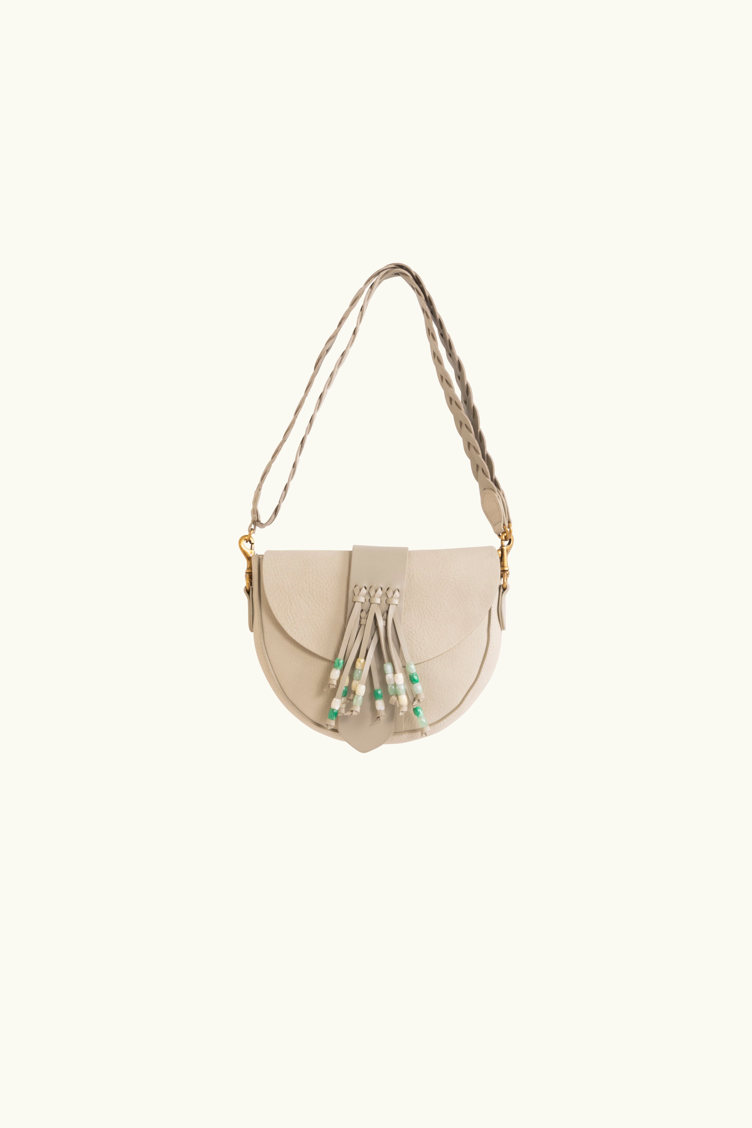 A natural coloured leather pouch with a braided strap and a belt style magnetic closure and tassel ties tipped with green beads.