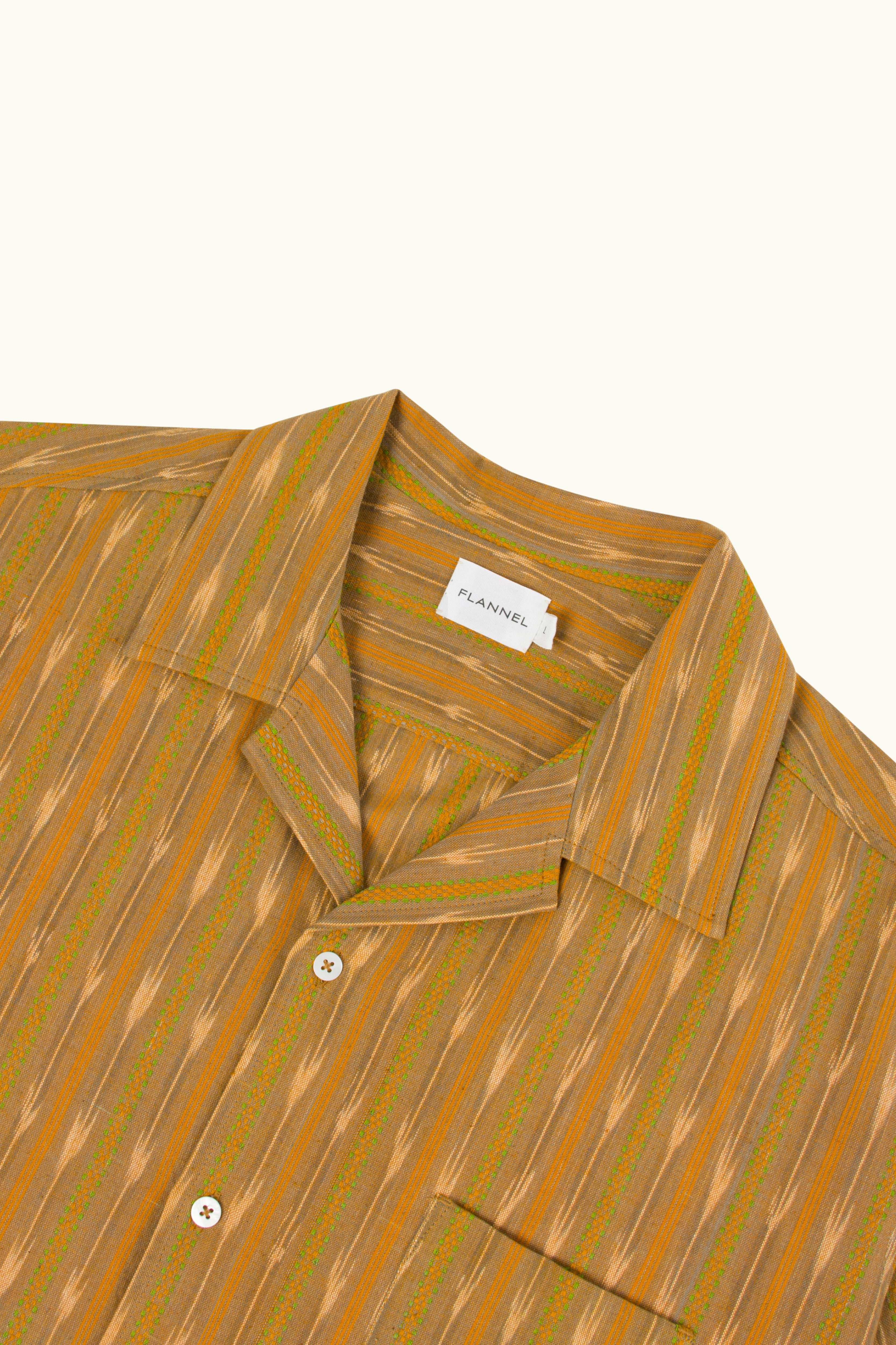 Close-up shot of a yellow ikat patterned shirt with collar and button details on a white background