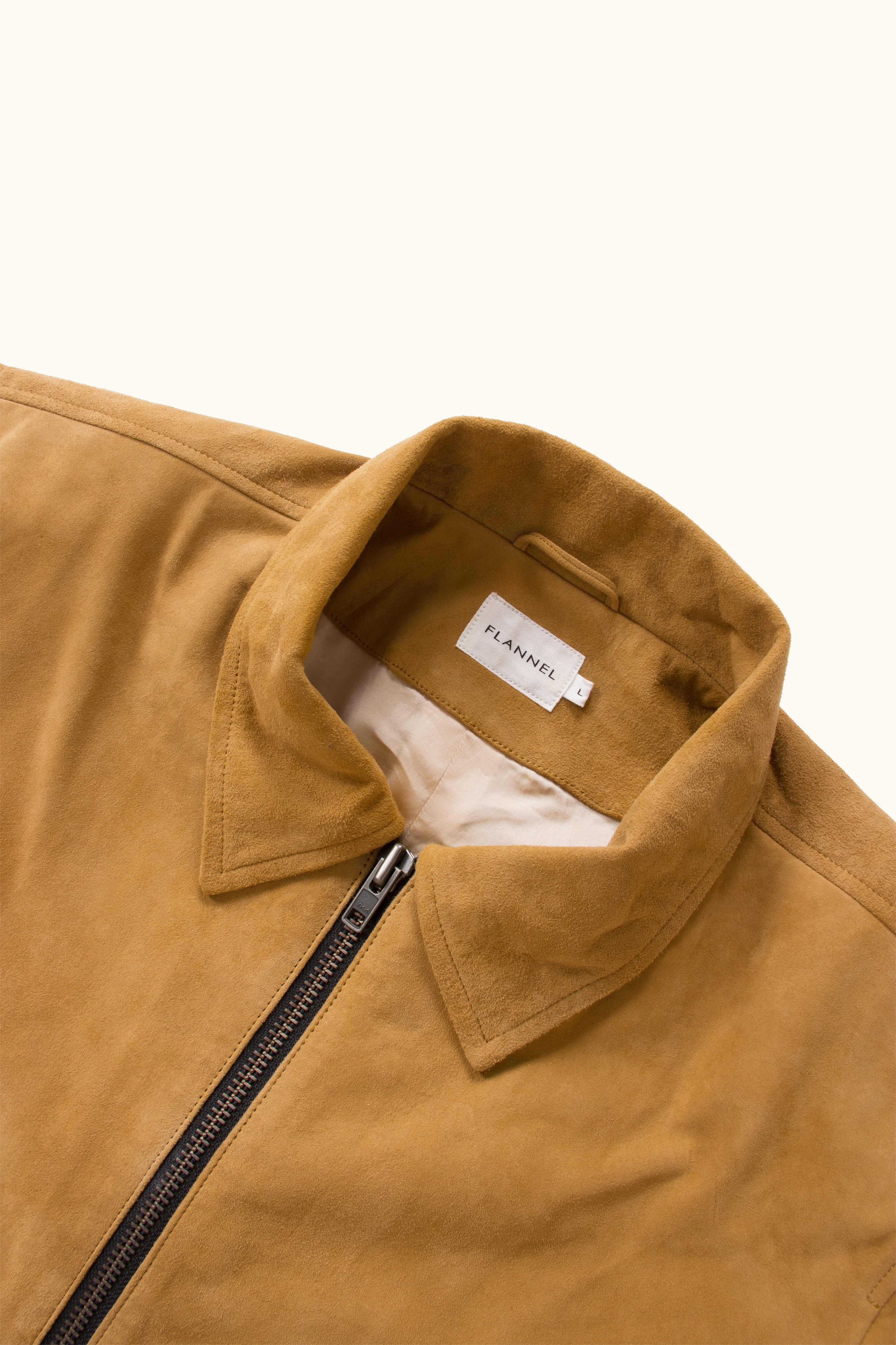 Close-up of a tan suede jacket collar on a white background