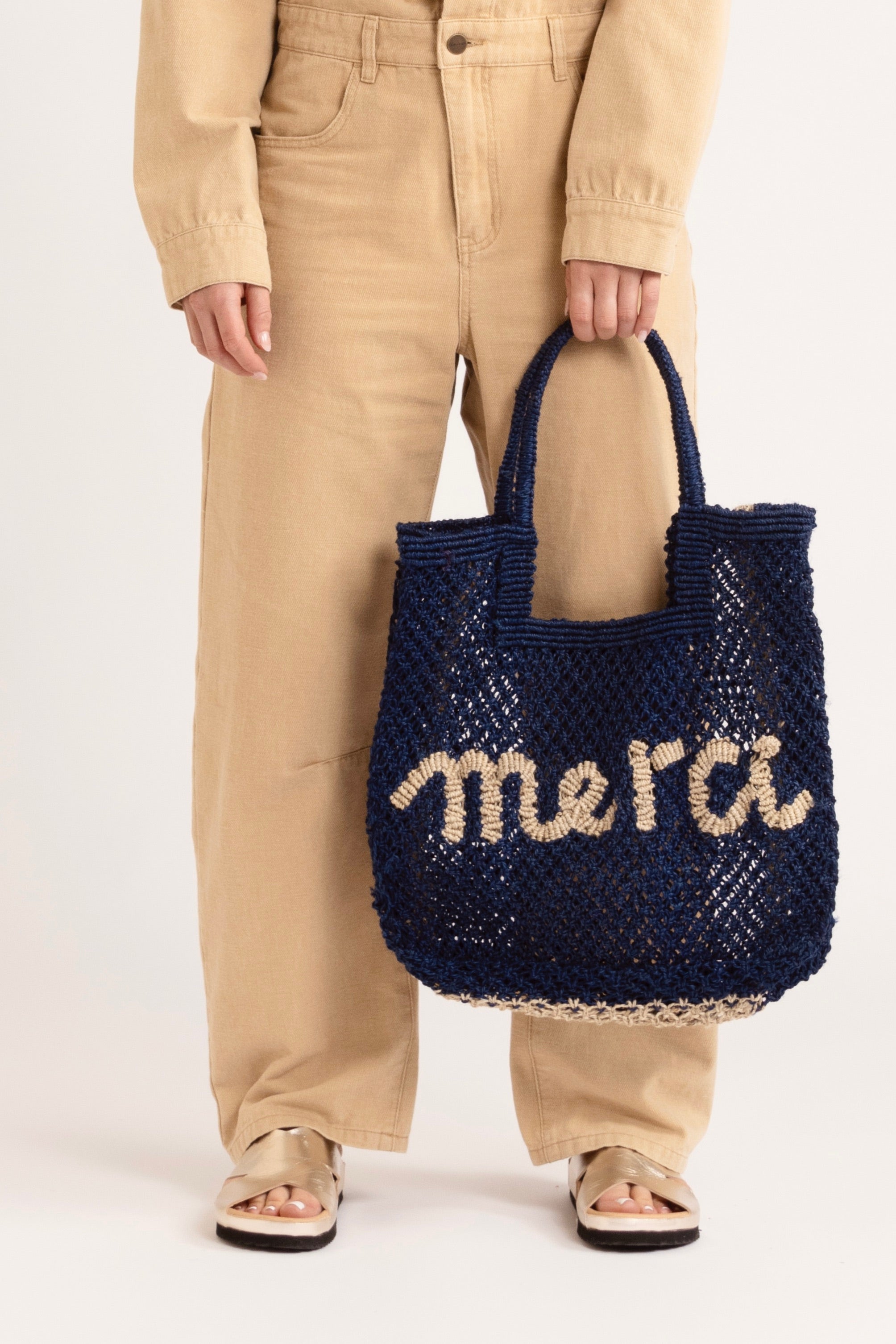 image of model wearing a brown jumpsuit holding a navy raffia bag.