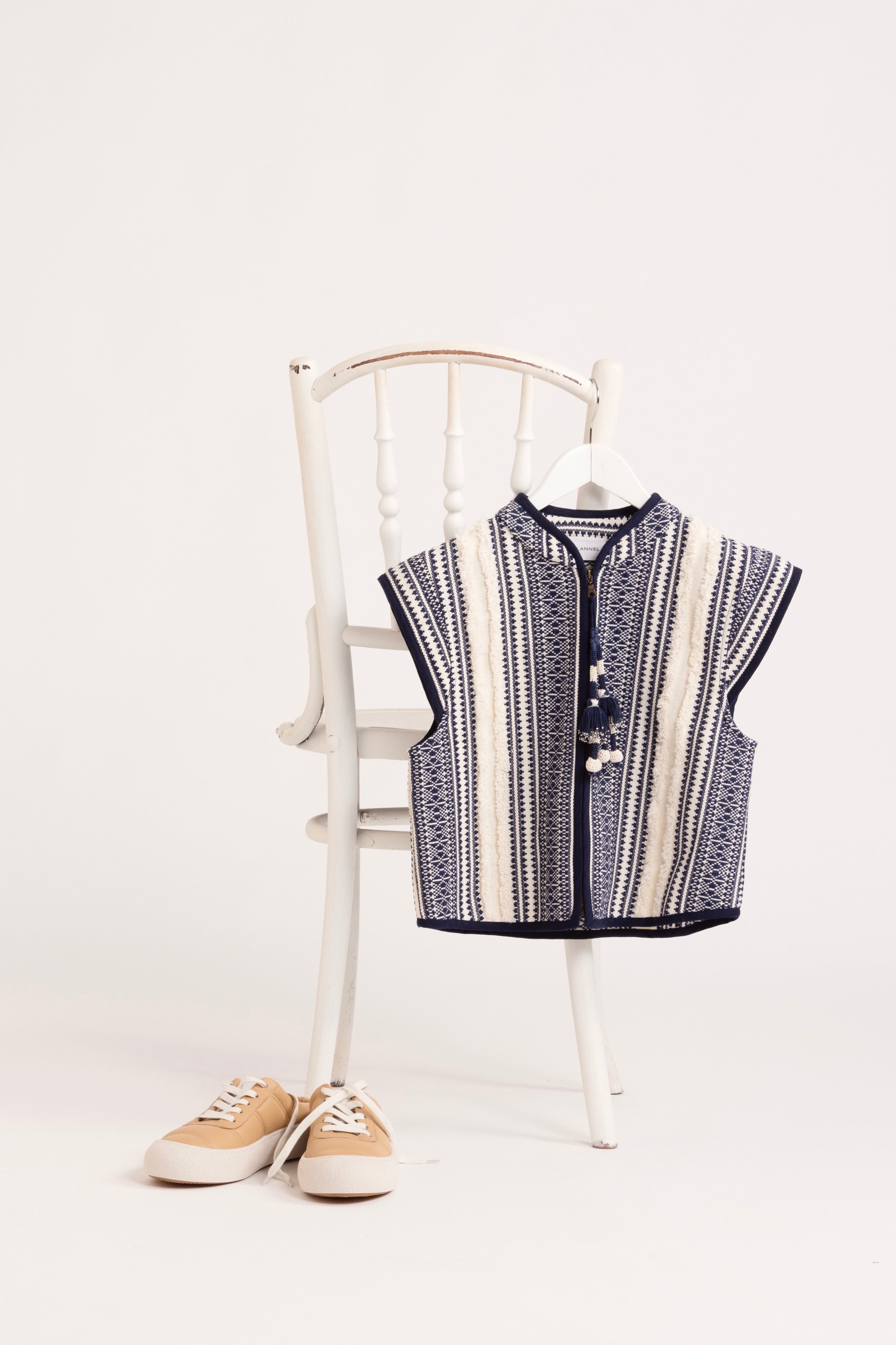 In situ image of blue and white striped vest hanging on a white chair.