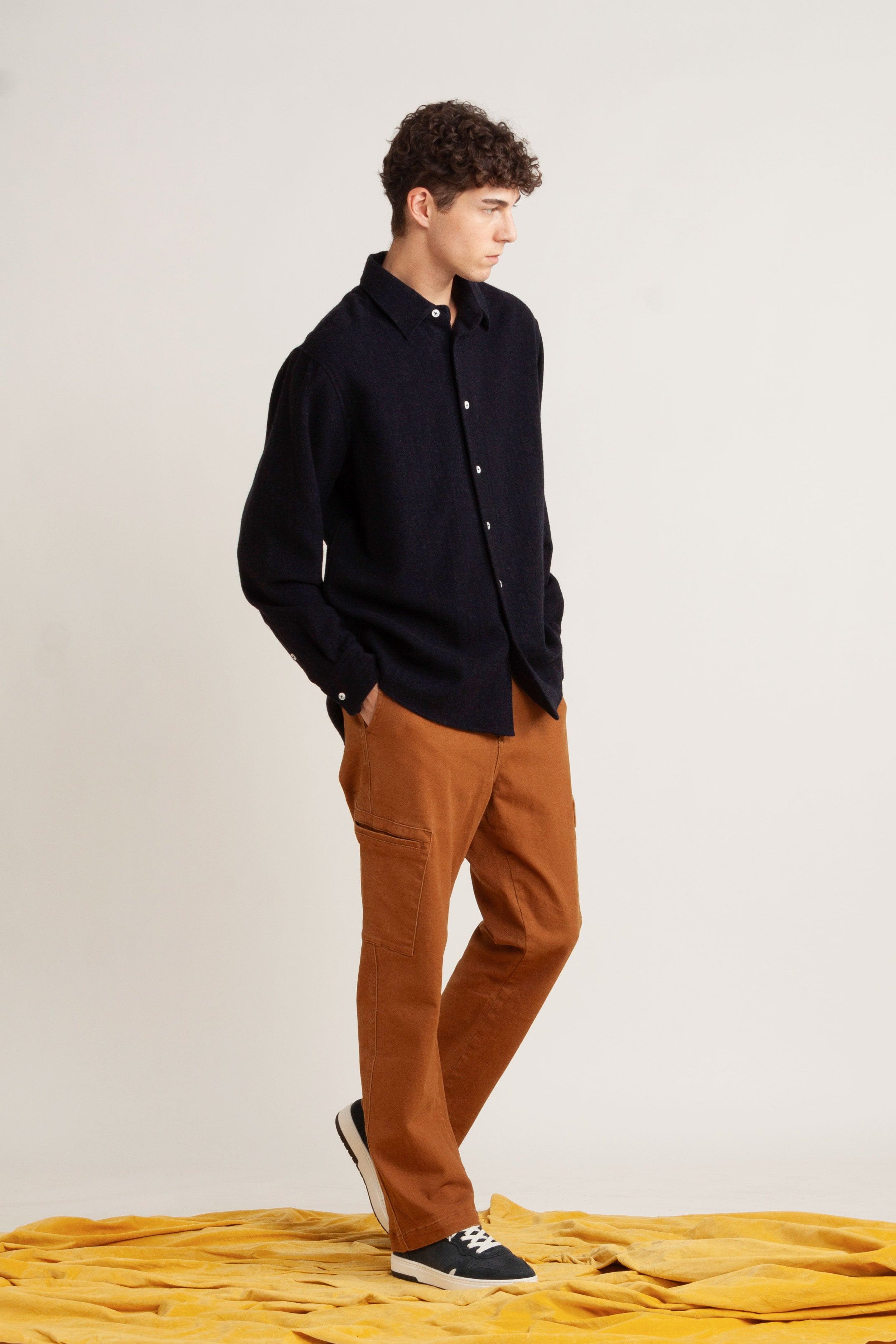 model wearing navy cotton long sleeve shirt, with burnt orange cotton pant and navy sneakers, front/side view