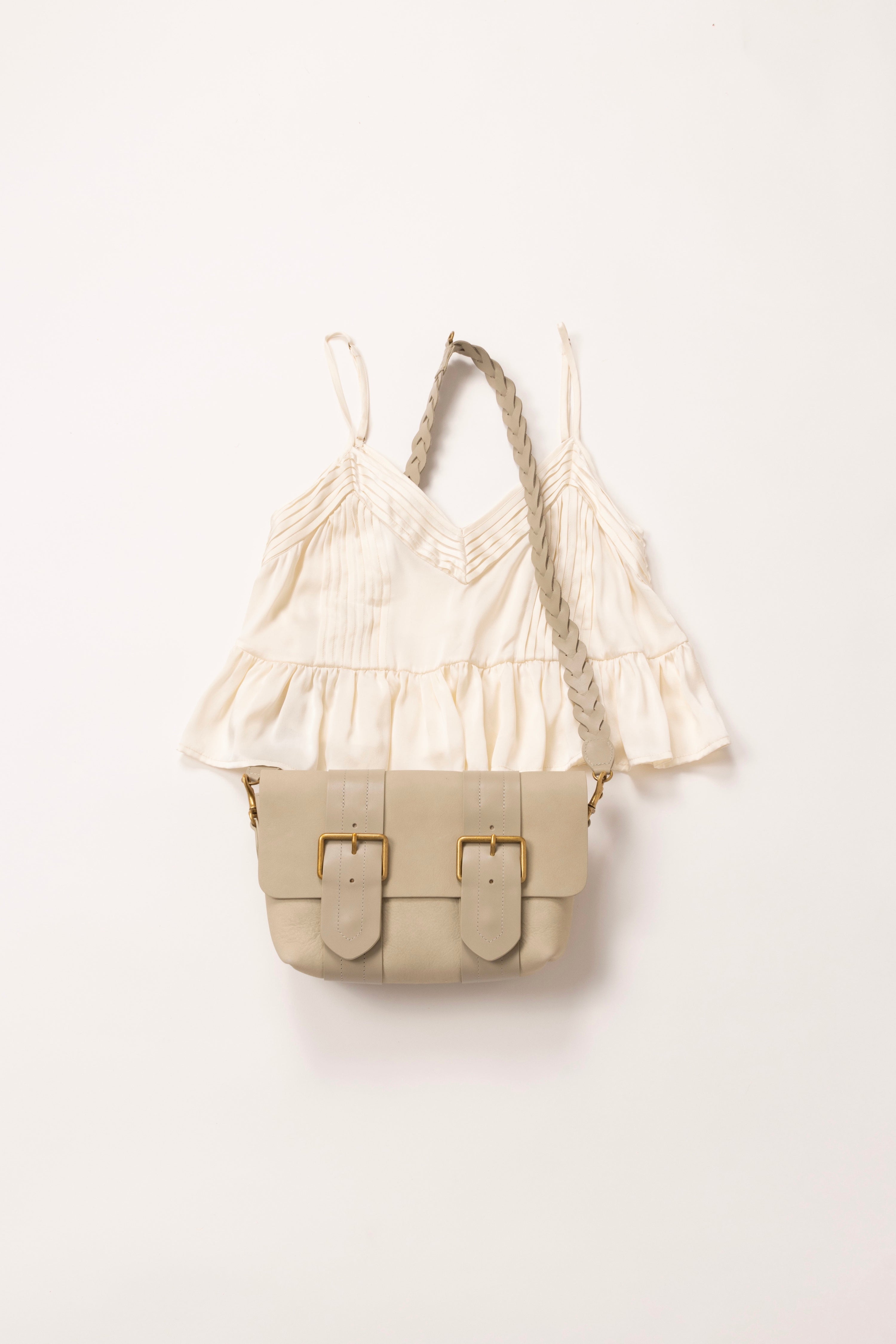 In situ image of white cami with a cream leather pouch placed on top.