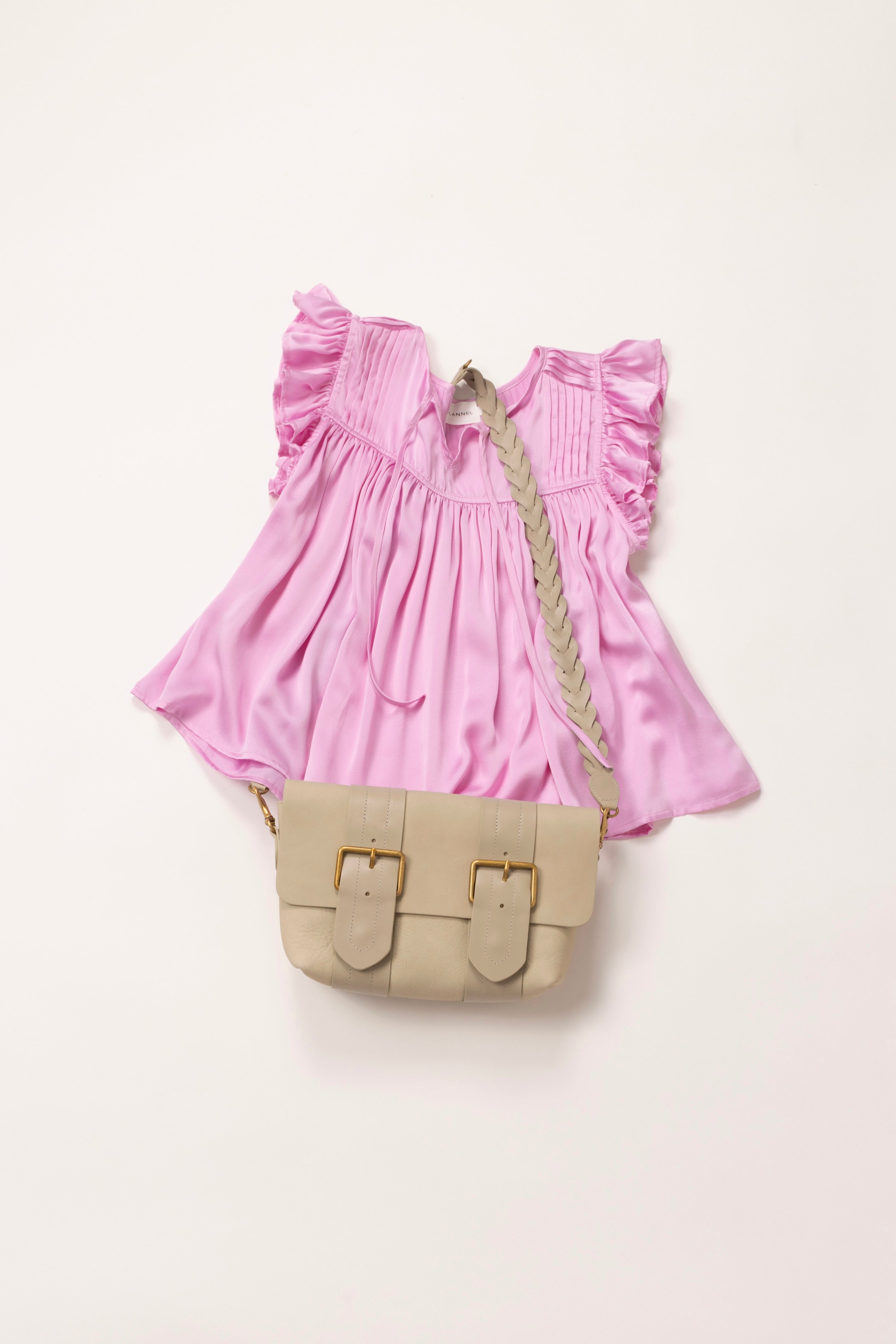 In situ image of pink sleeveless top with a leather pouch placed on top.