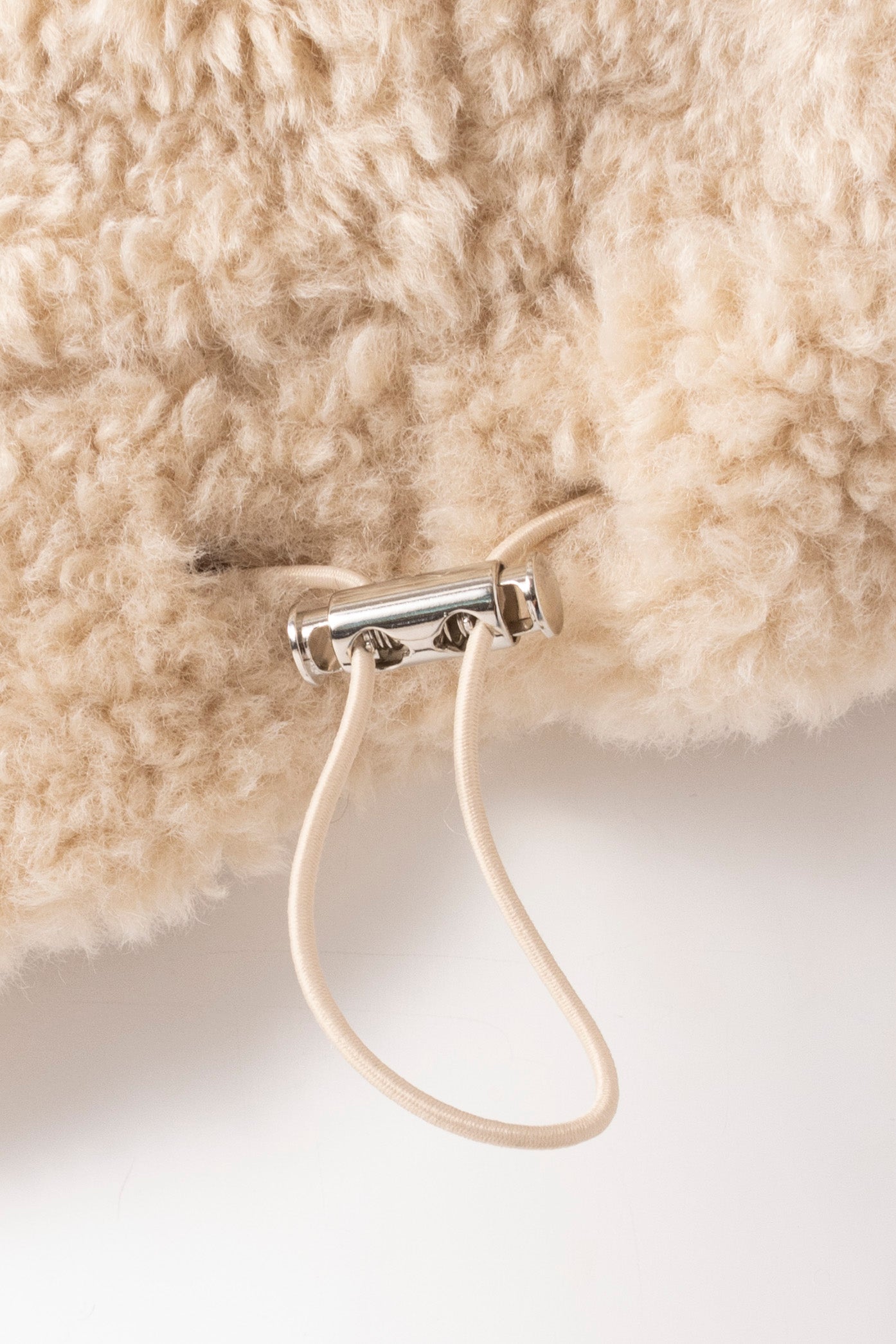 Close up image of elasticated waistband of an oat coloured faux fur vest