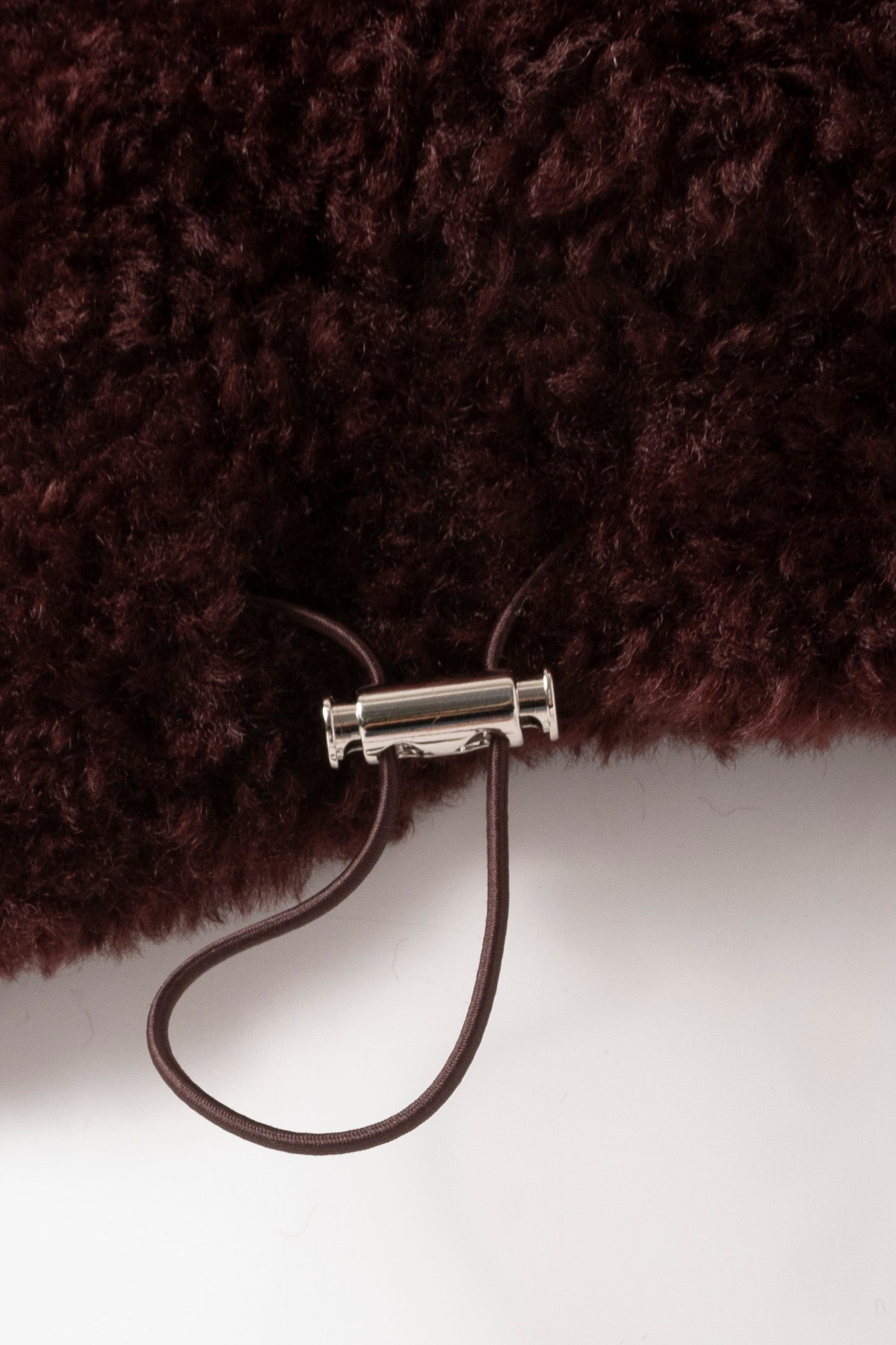 Up close image of elasticated waistband of a port coloured faux fur jacket