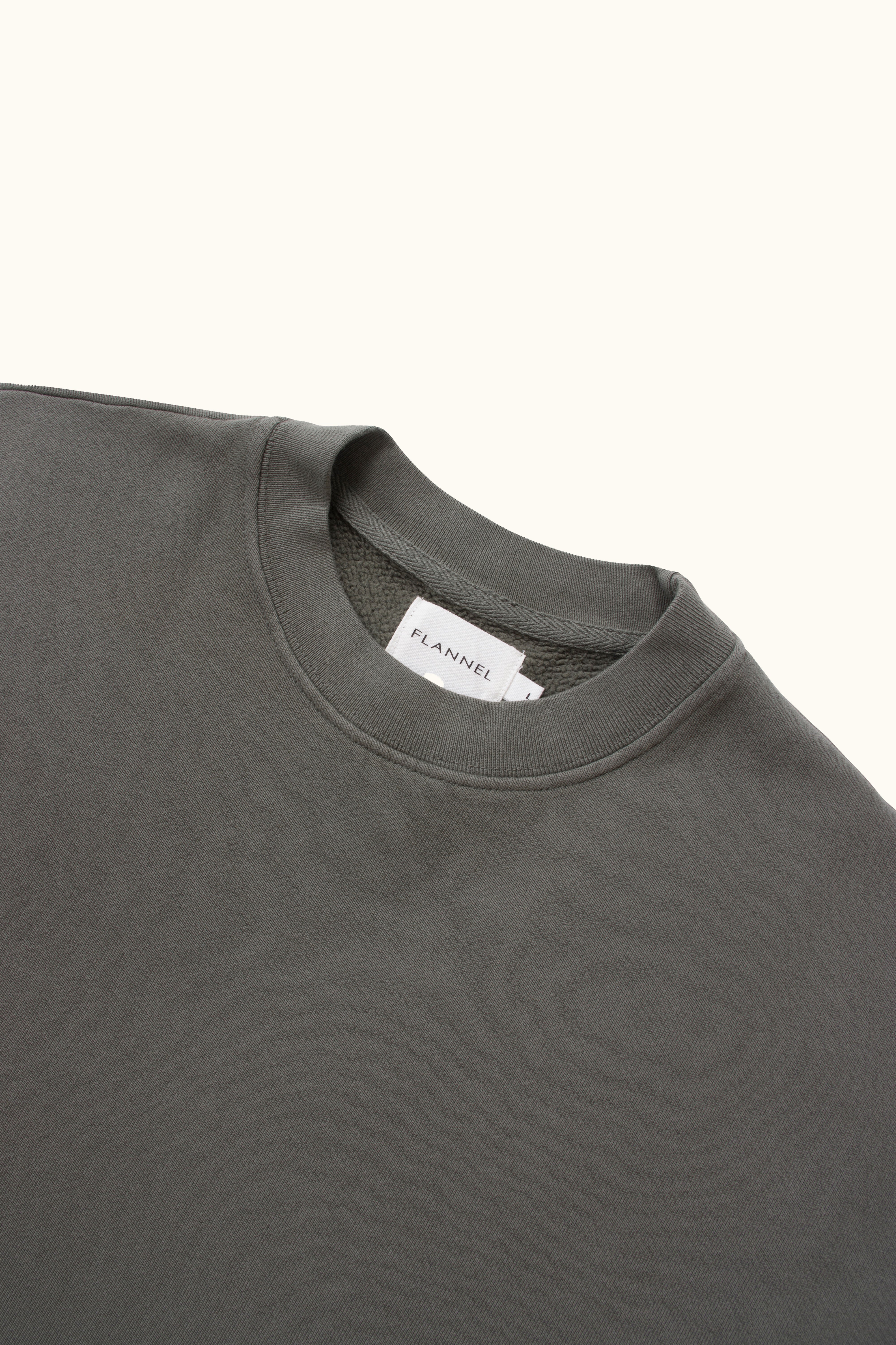 Close-up of a dark gray sweater with a brand label on a white background