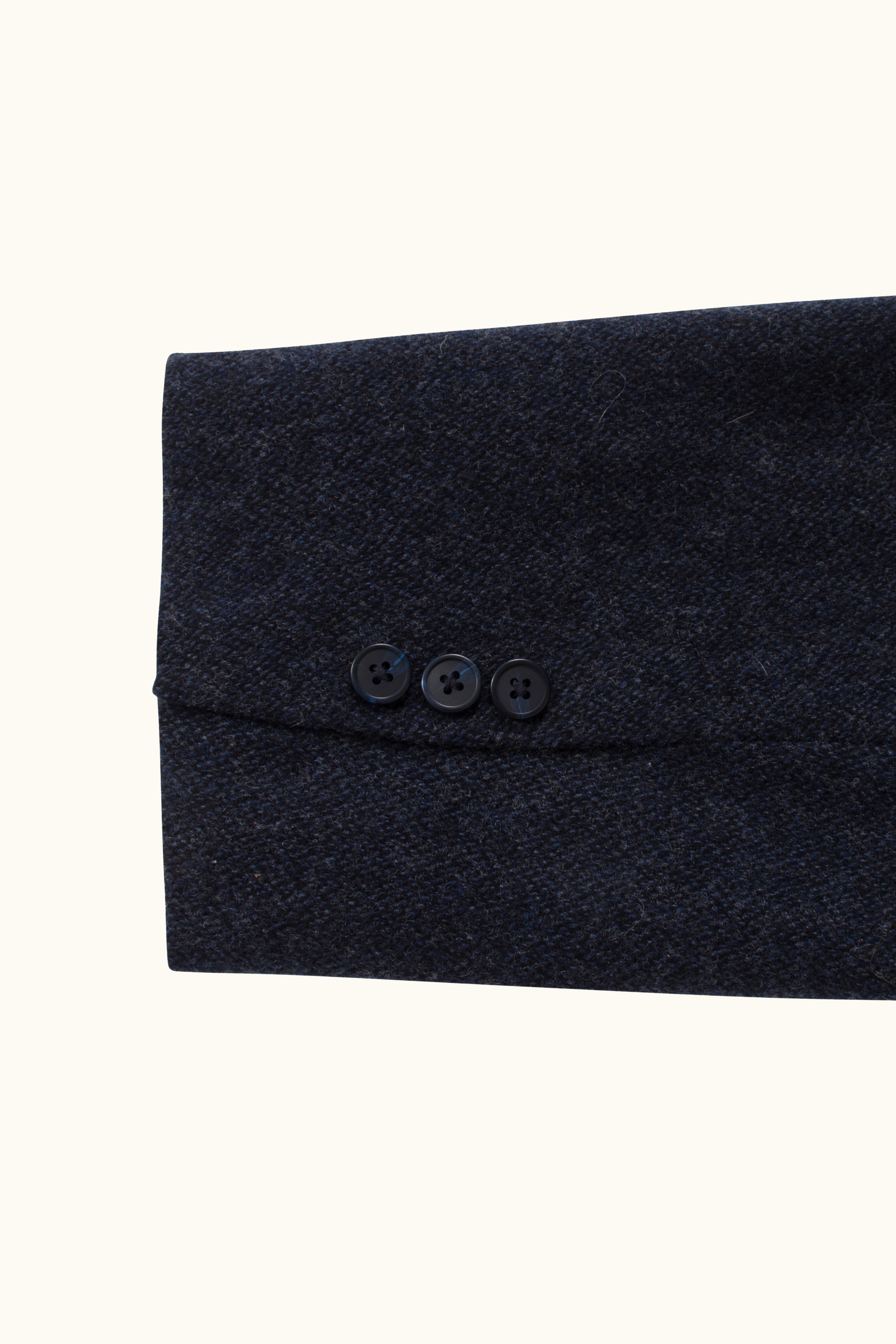 Close-up of a dark navy wool fabric with buttons on a white background