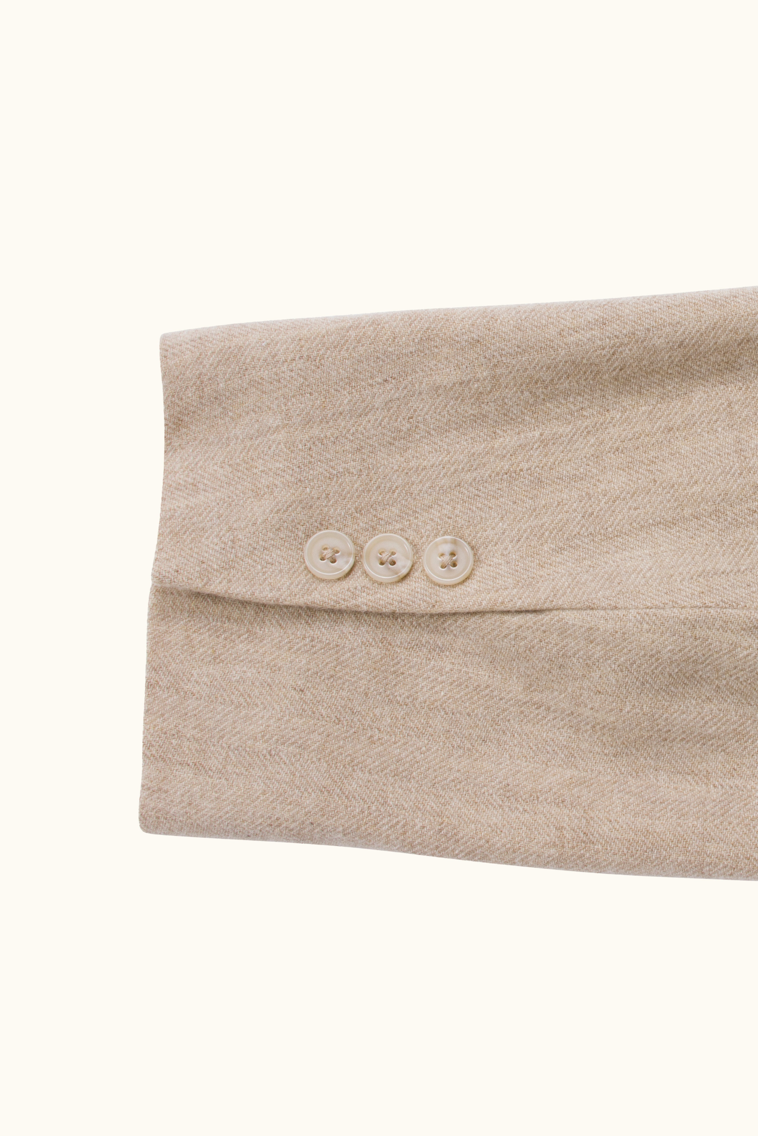 Close-up of a beige wool fabric with three buttons on a white background