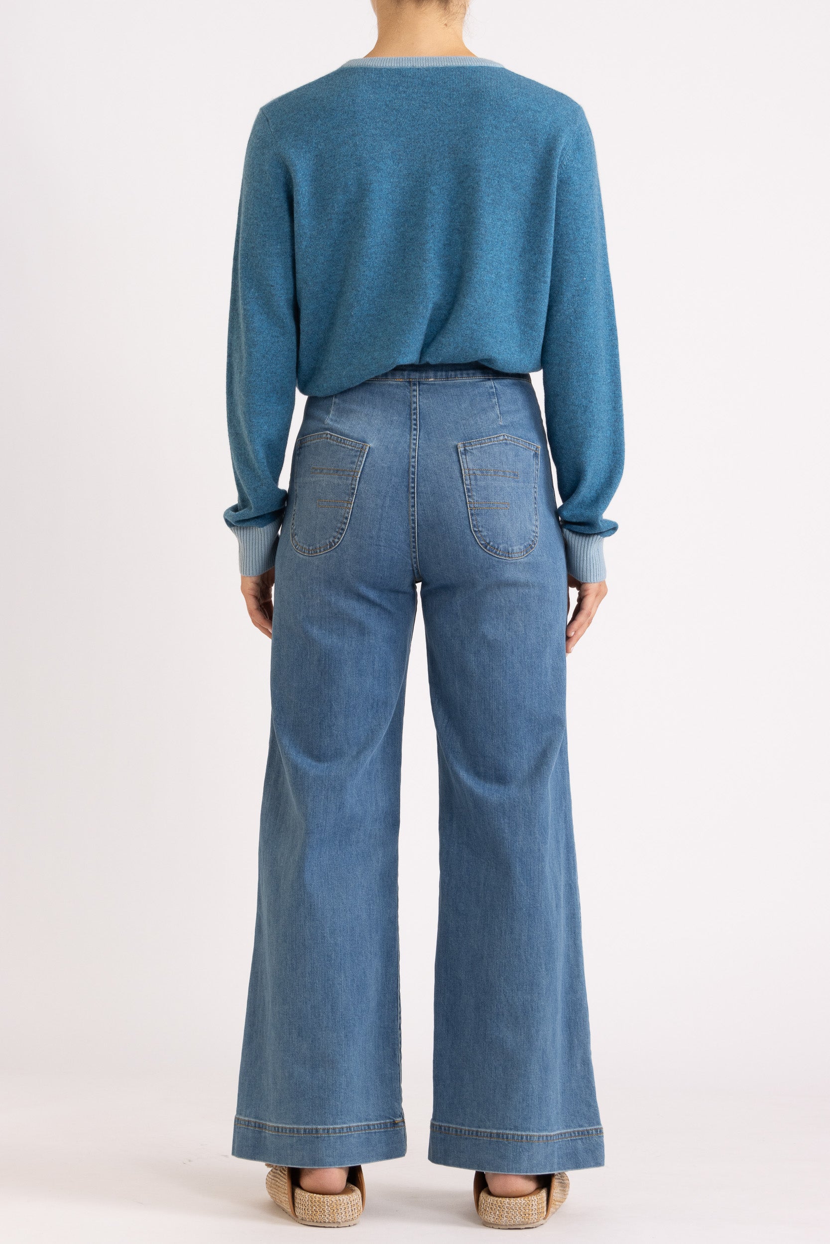 Woman wearing a two toned blue cashmere cardigan paired with blue denim jeans