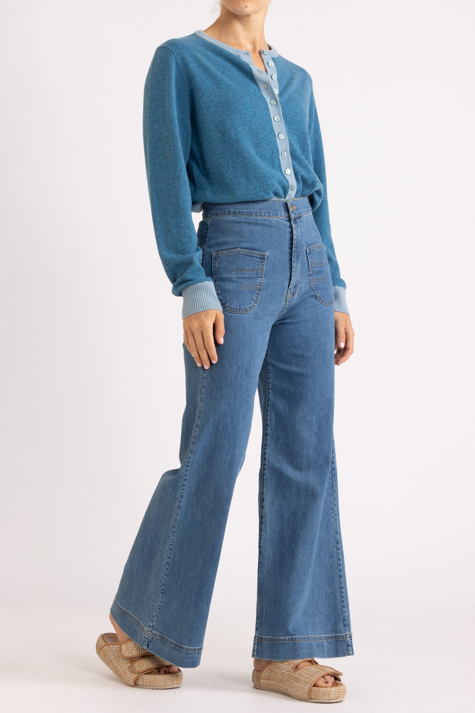 Woman wearing a two toned blue cashmere cardigan paired with blue denim jeans
