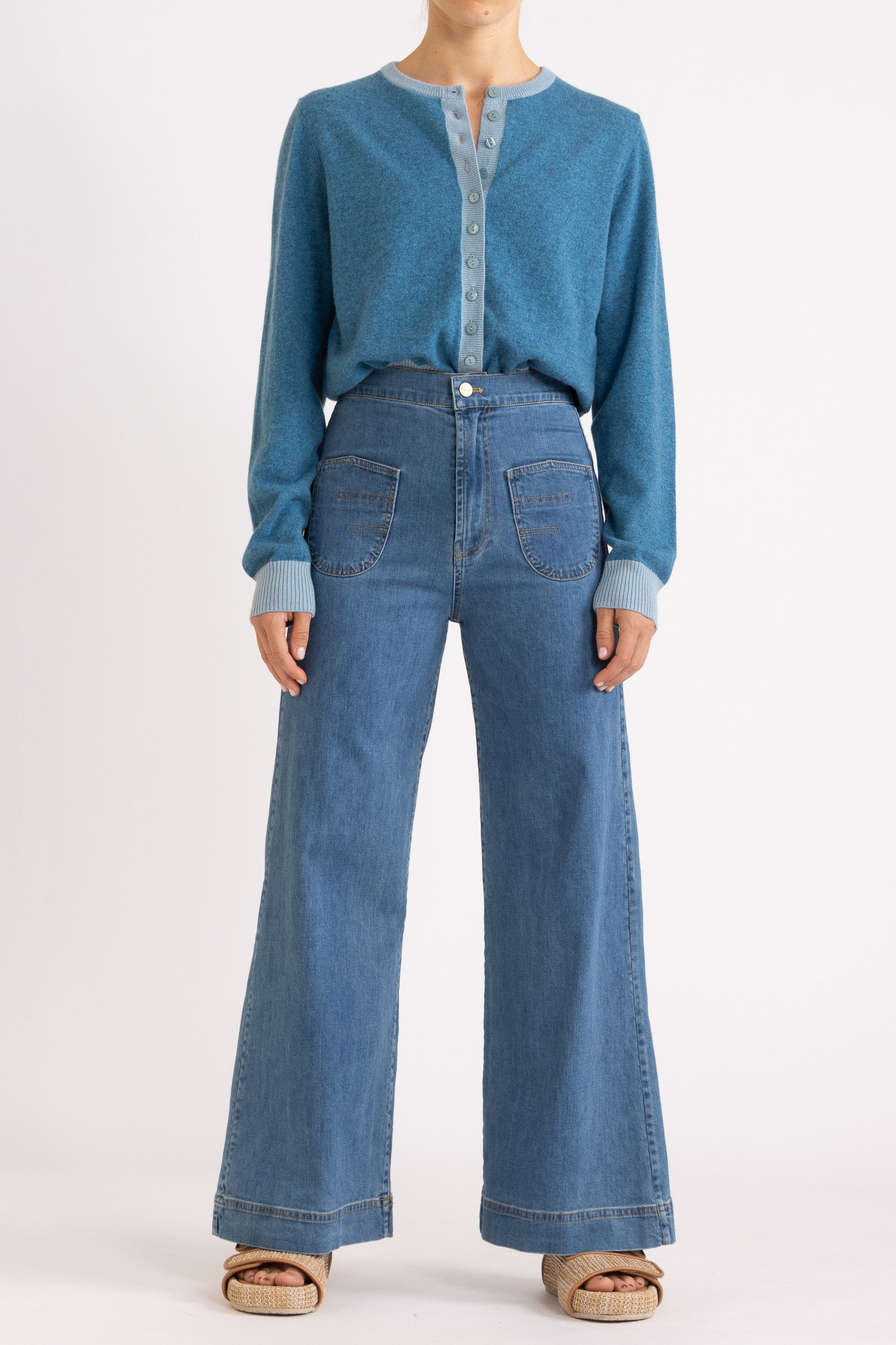 Woman wearing a two toned blue cashmere cardigan paired with blue denim jeans