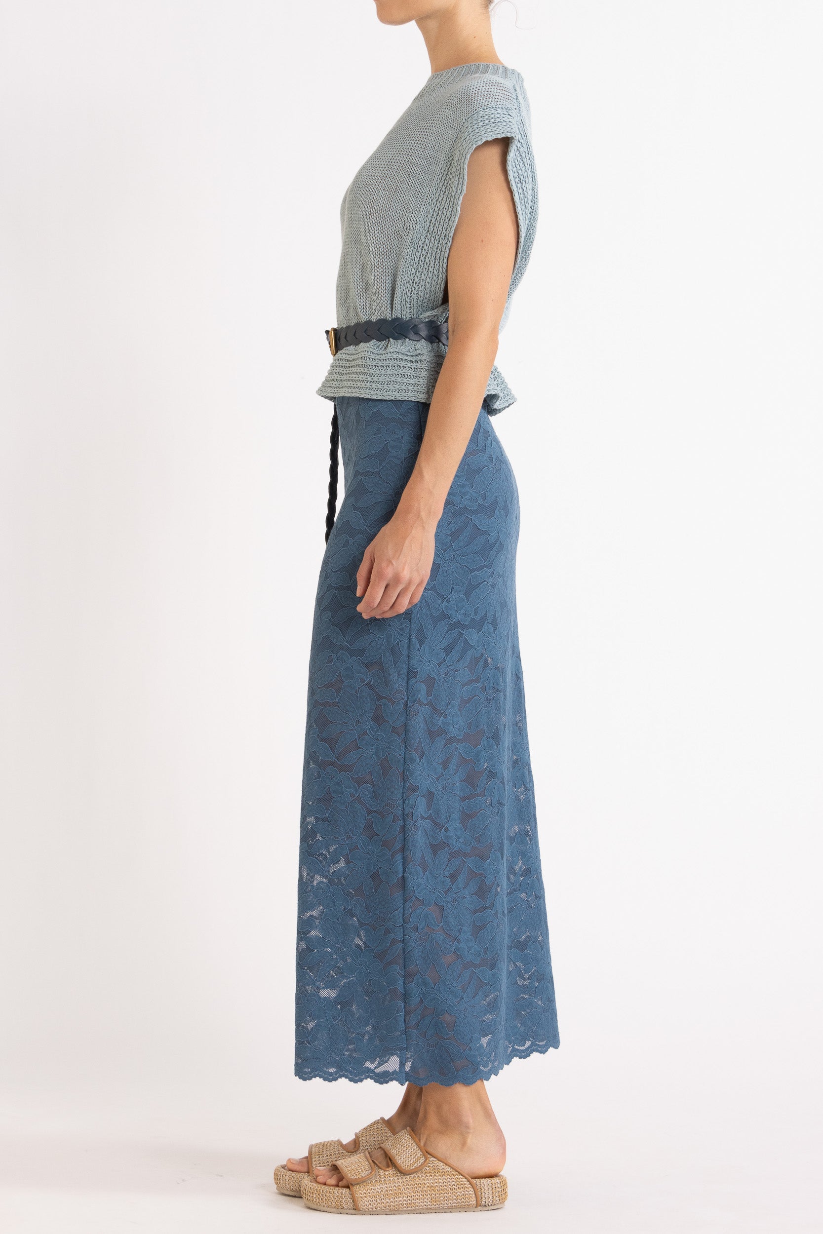 Woman wearing blue linen vest with a blue woven belt and blue floral lace maxi skirt