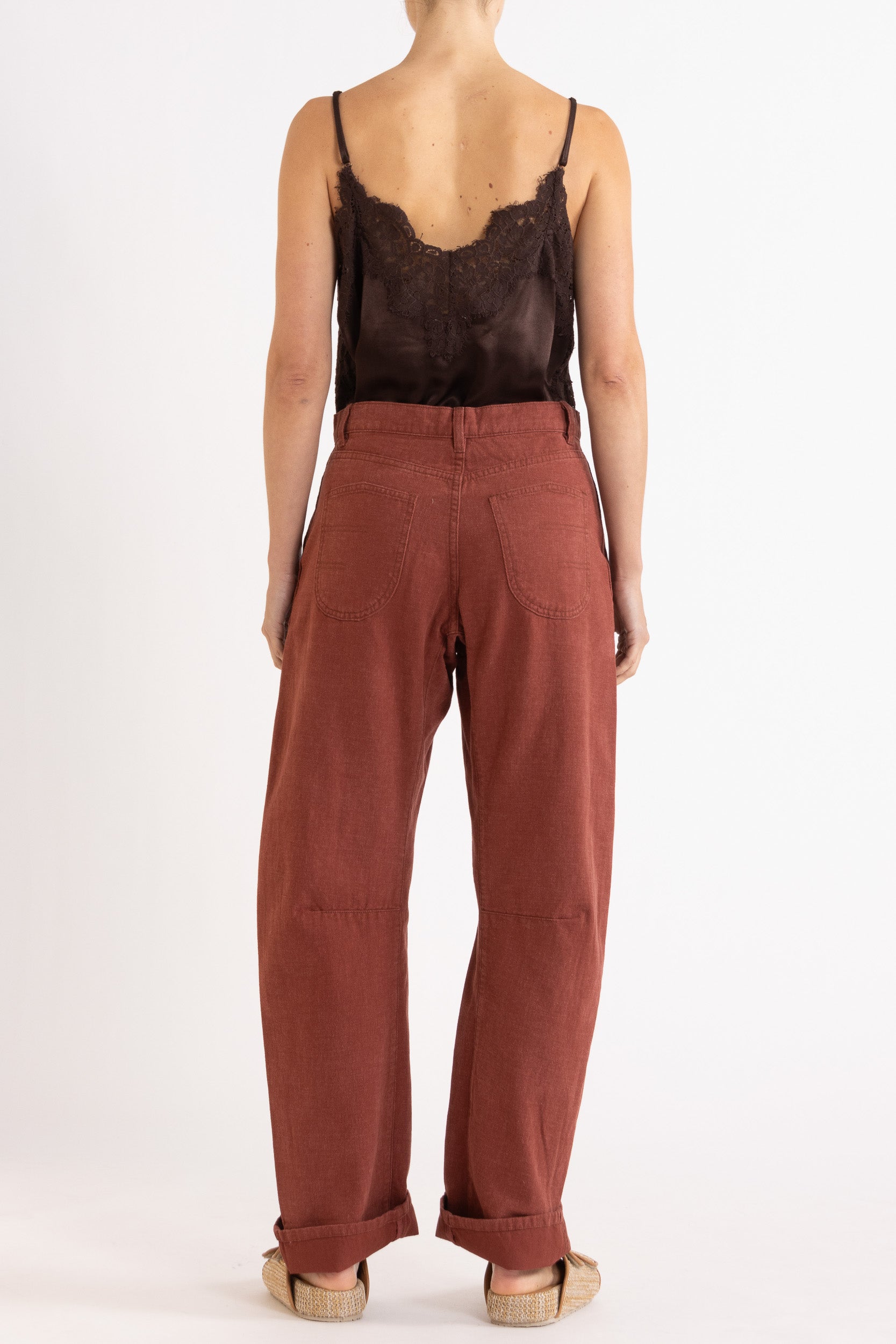 Model wearing chocolate satin cami with lace trims & burgundy cotton-twill pant, back view