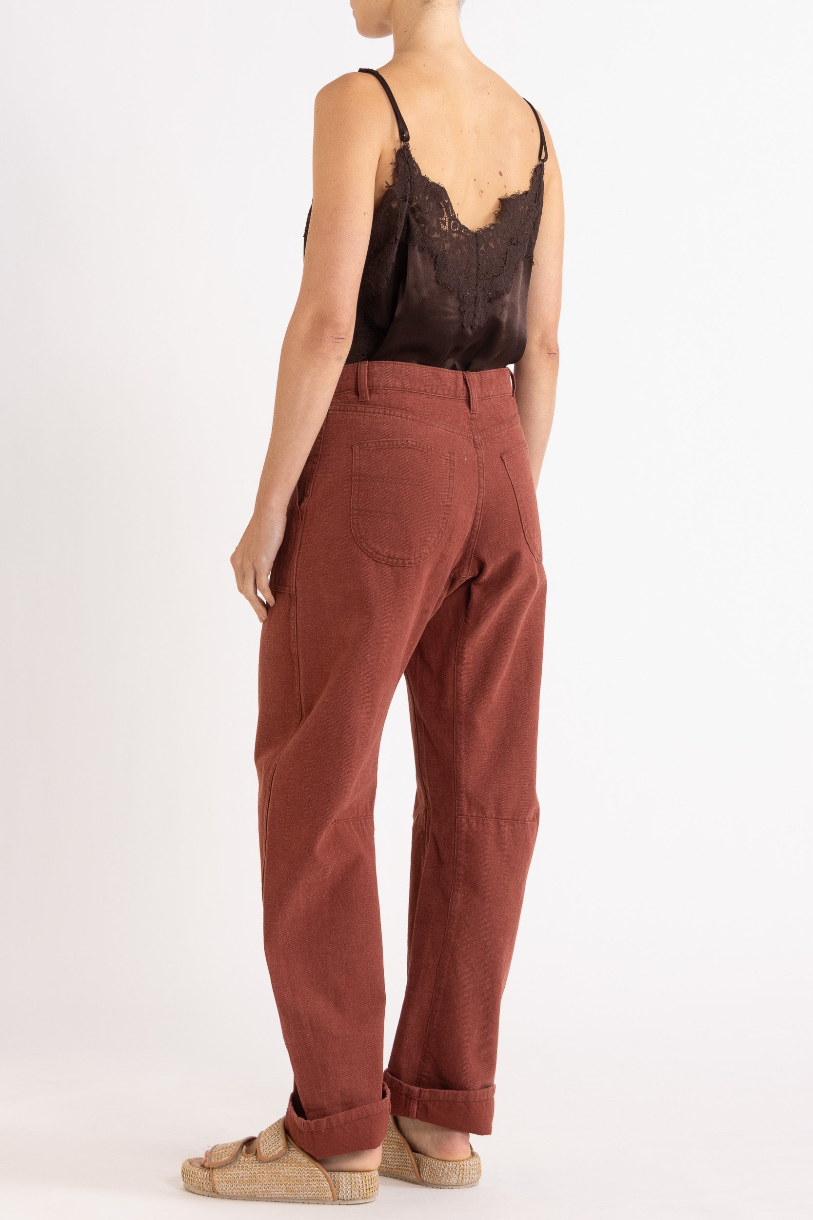 Model wearing chocolate satin cami with lace trims & burgundy cotton-twill pant, back-side view