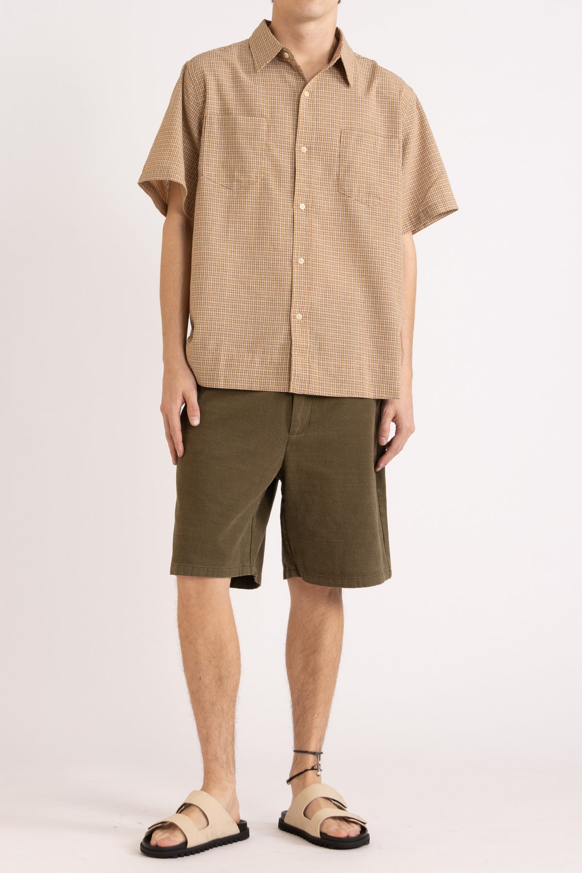 Model wearing a camel check cotton shirt and olive cotton shorts on a white background, front view