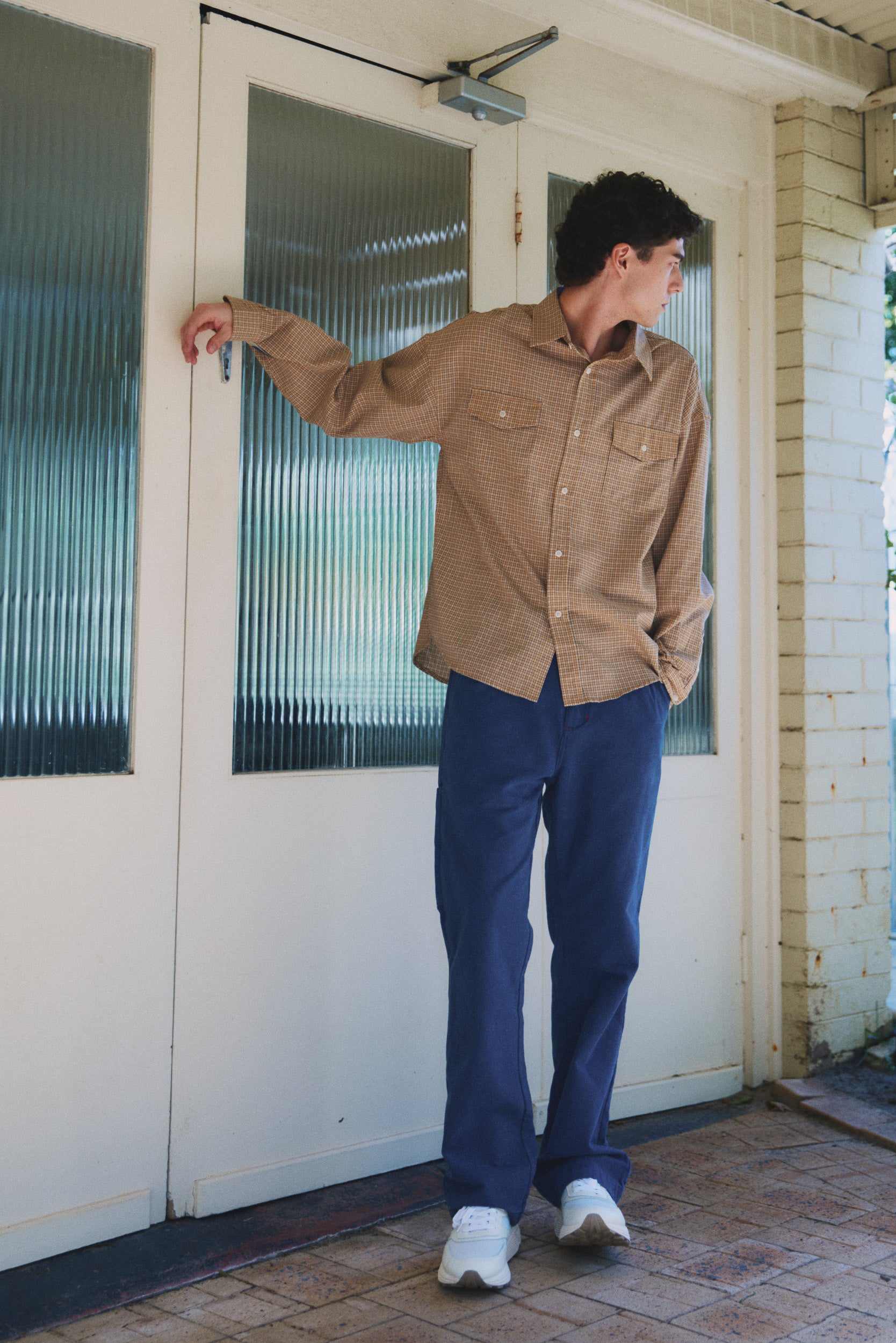 Model wearing camel check cotton shirt with blue cotton pant and white sneakers, campaign image