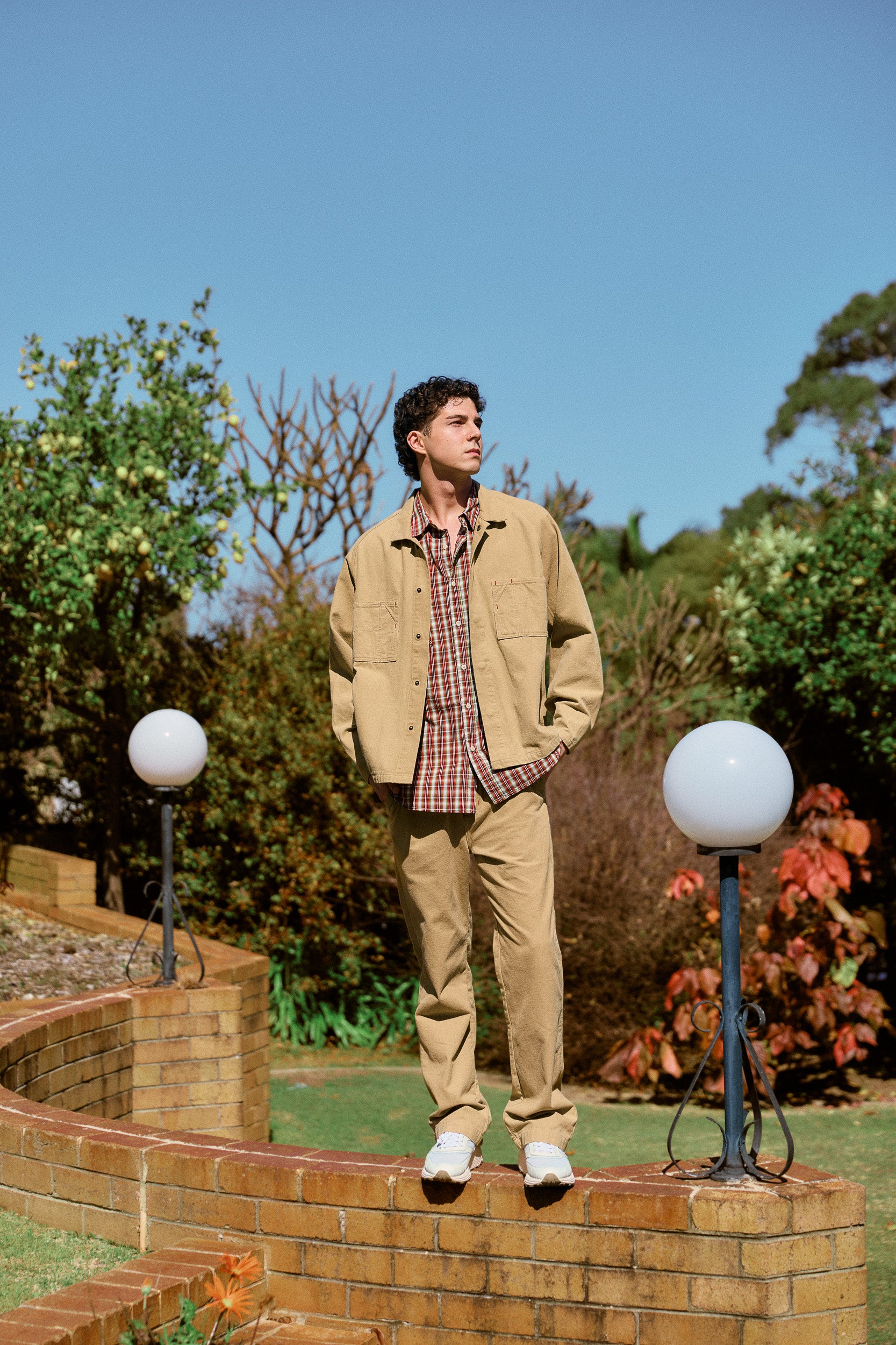 model wearing sand cotton jacket, red and white cotton shirt, sand cotton pant & white sneaker, campaign image