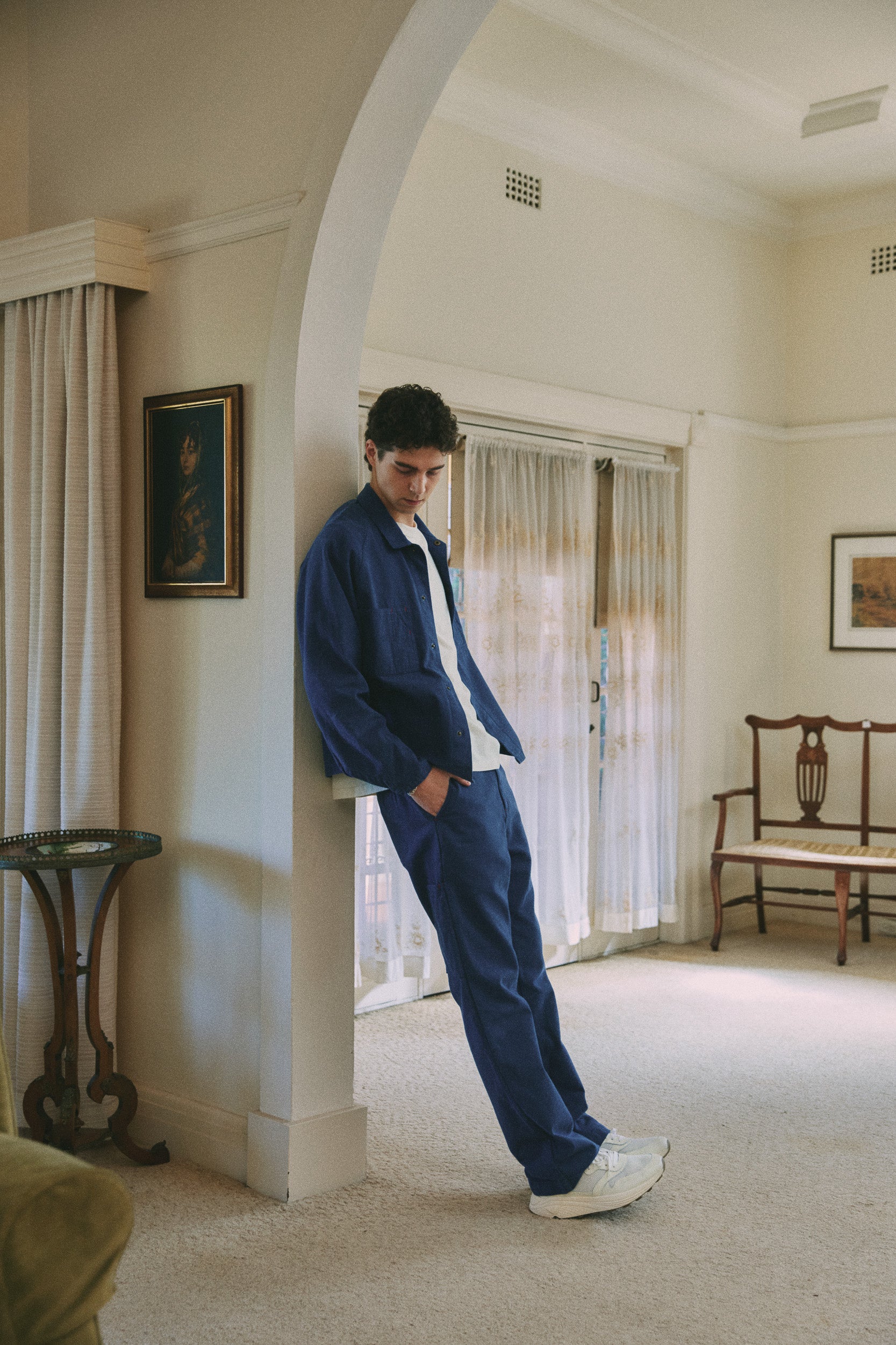 Model wears blue cotton jacket and pant with white cotton t-shirt and white sneakers, campaign image