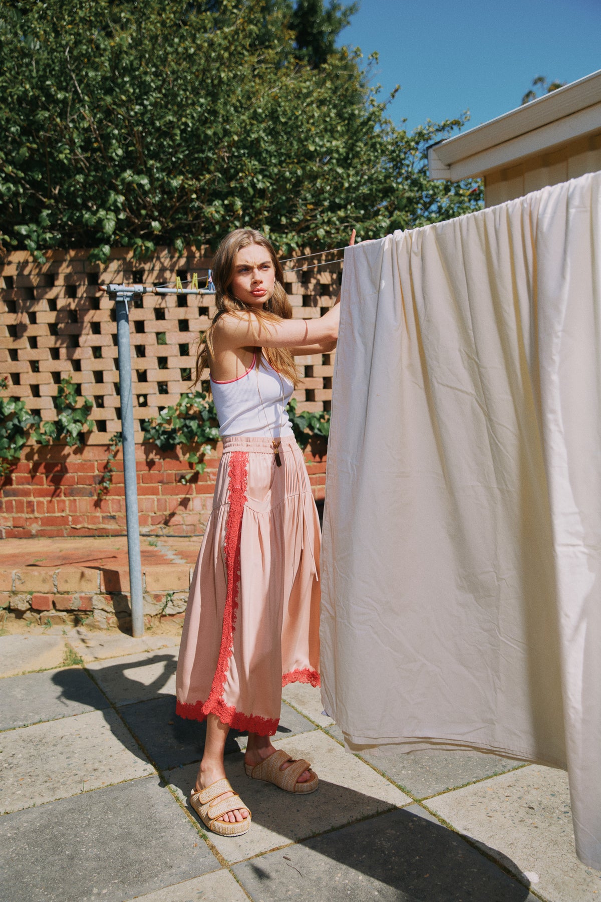 Model wearing white ribbed singlet & pink skirt with red lace trim, campaign image