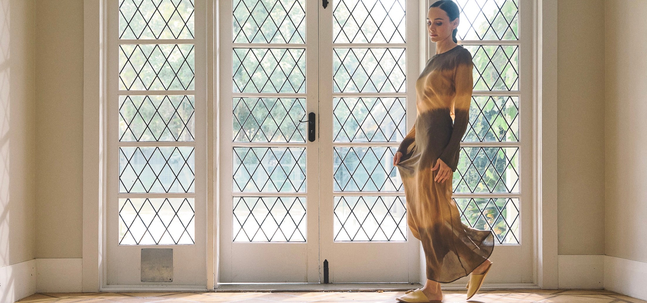 Landscape image of model wearing earthy toned dip dye silk habotai long sleeve dress.