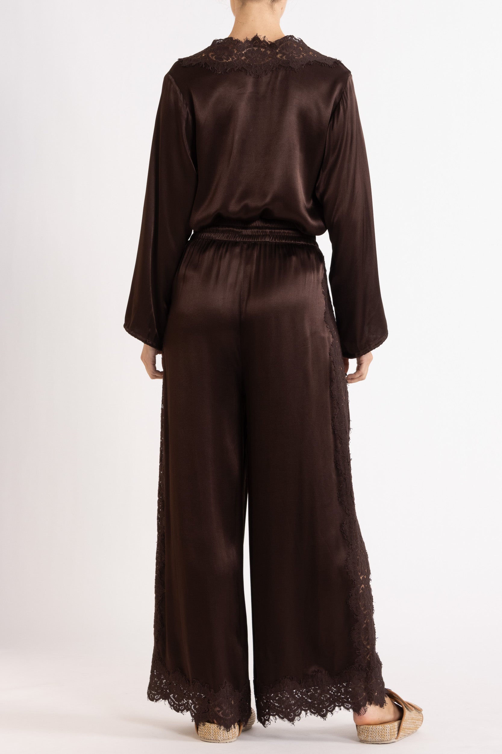 Woman wearing a brown long sleeve top and pant with lace details on a white background