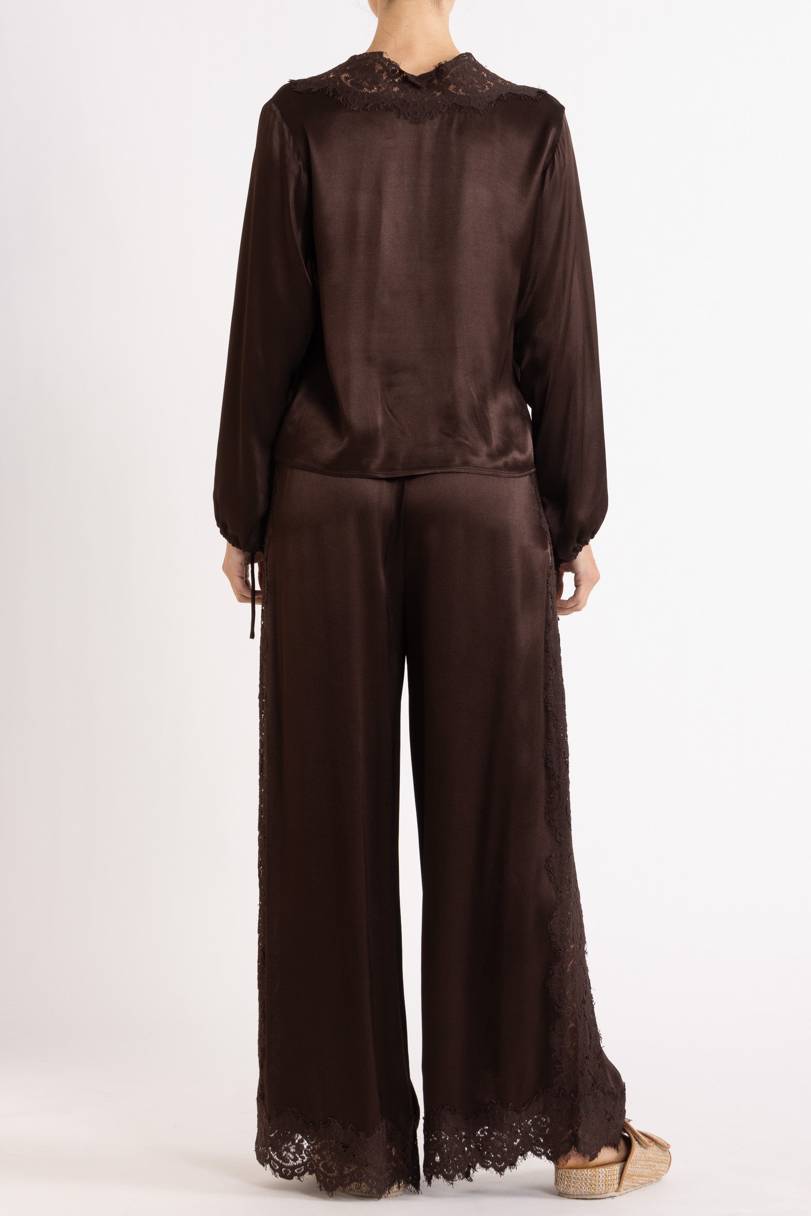 Woman wearing a brown long sleeve top and pant with lace details on a white background