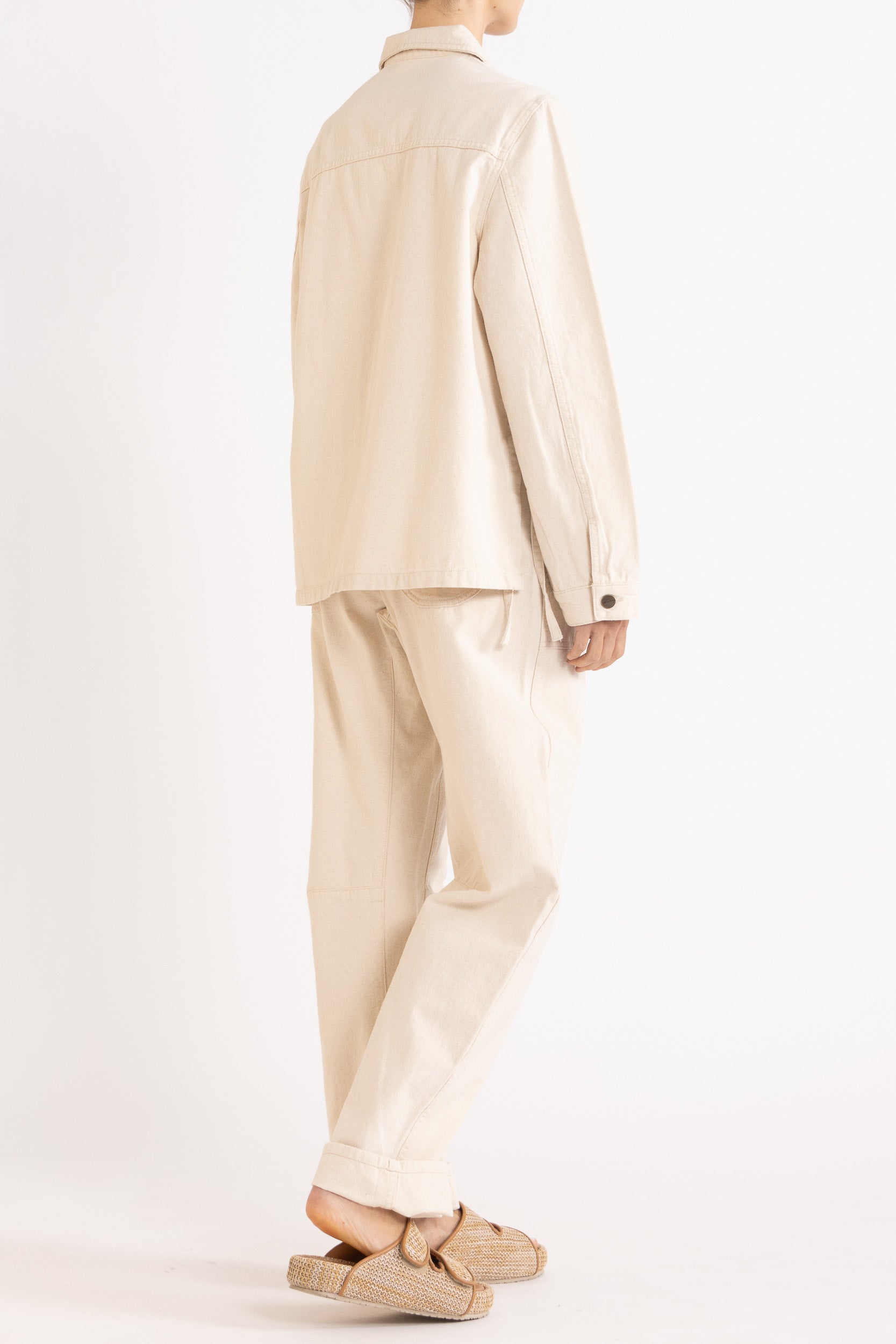 Model wearing cream cotton-twill utility jacket & pant, back-side view