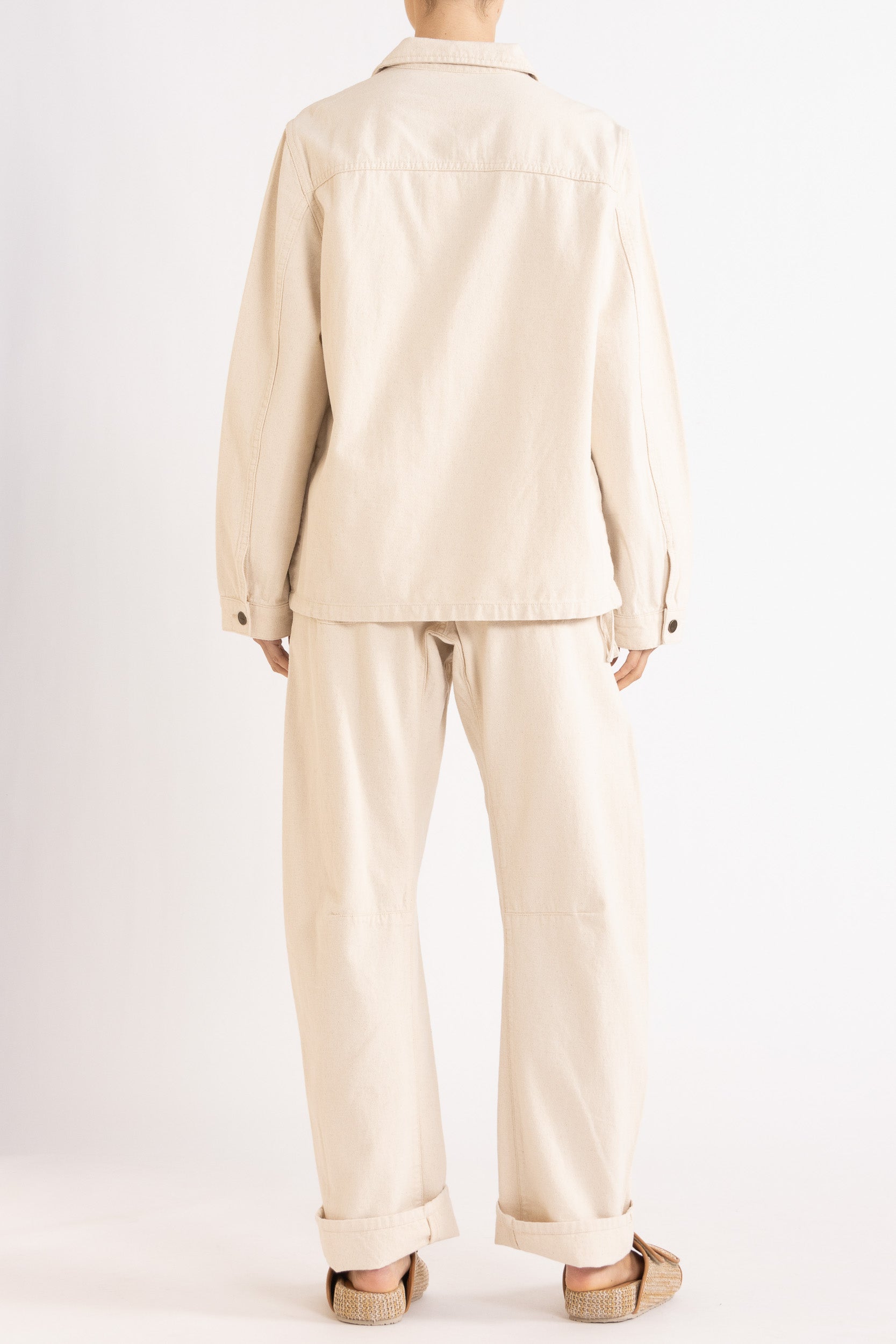 Model wearing cream cotton-twill utility jacket & pant, back view
