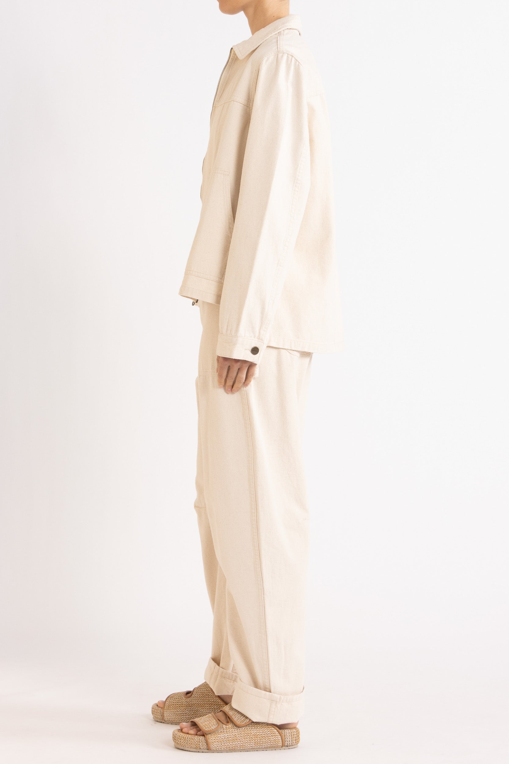 Model wearing cream cotton-twill utility jacket & pant, side view