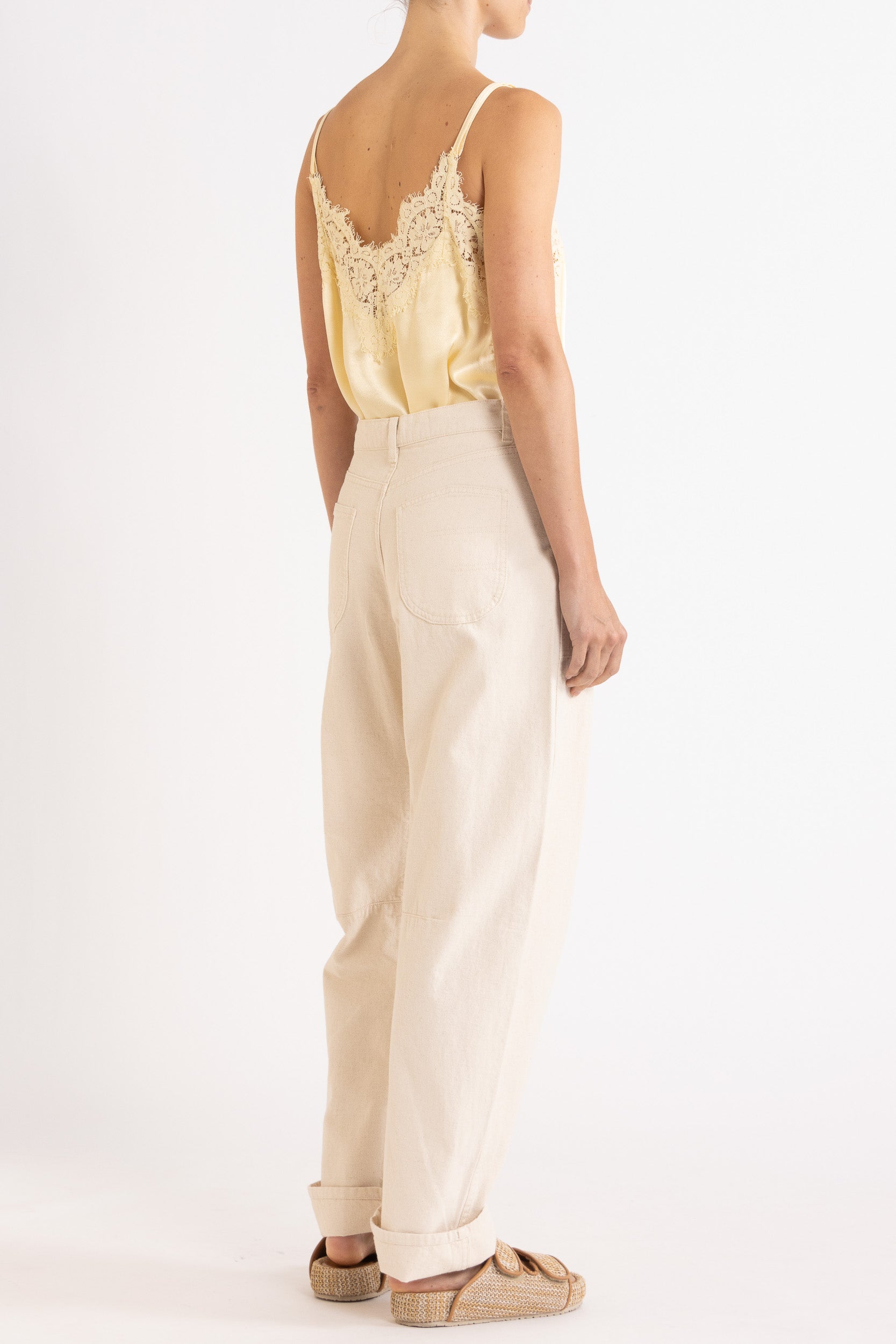 Model wearing pale yellow satin cami with lace trims & cream cotton-twill pant, back-side view