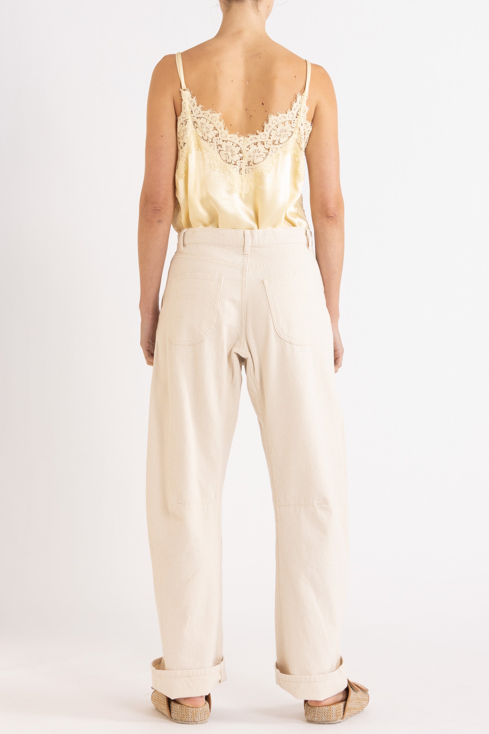 Model wearing pale yellow satin cami with lace trims & cream cotton-twill pant, back view