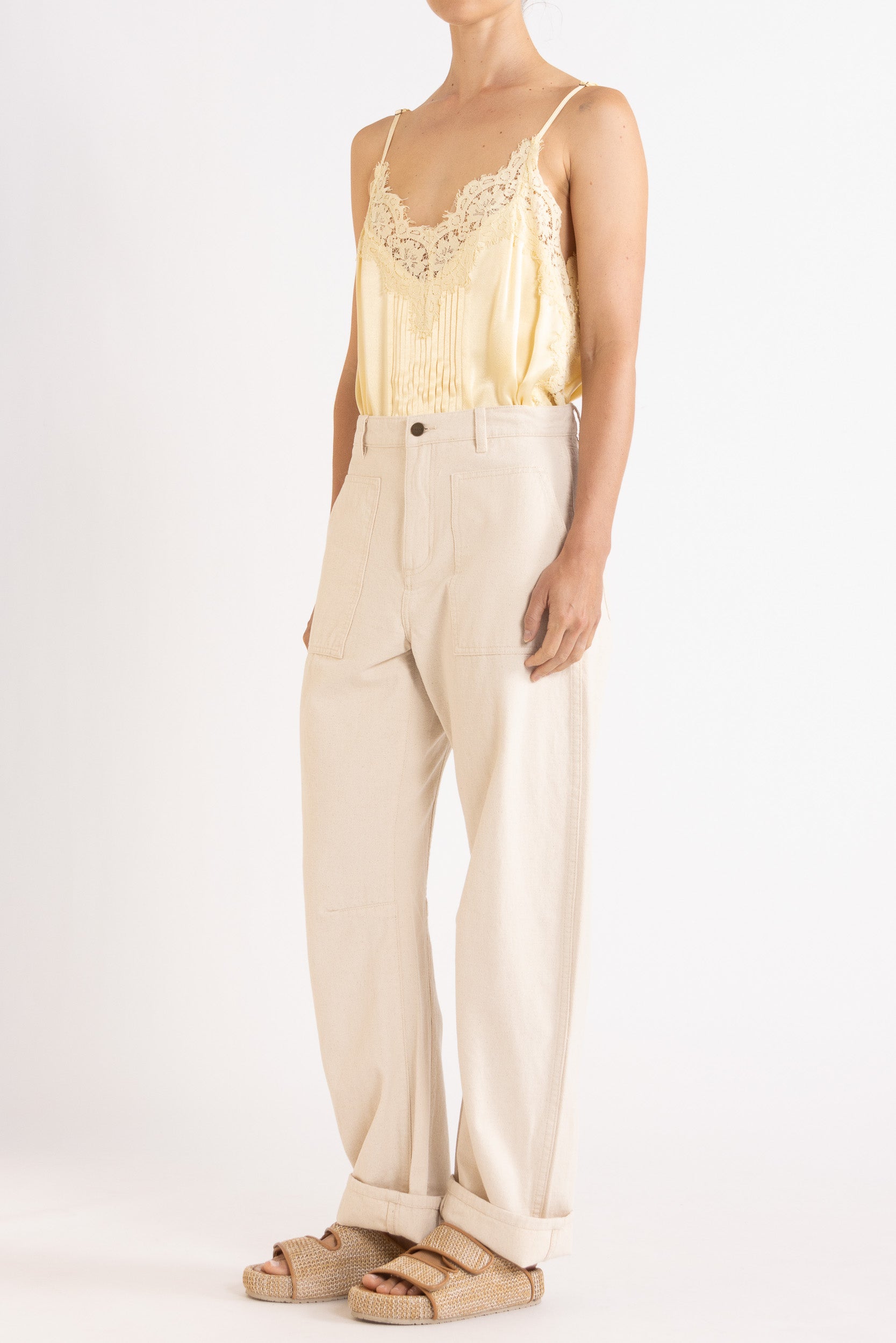 Model wearing pale yellow satin cami with lace trims & cream cotton-twill pant, front-side view