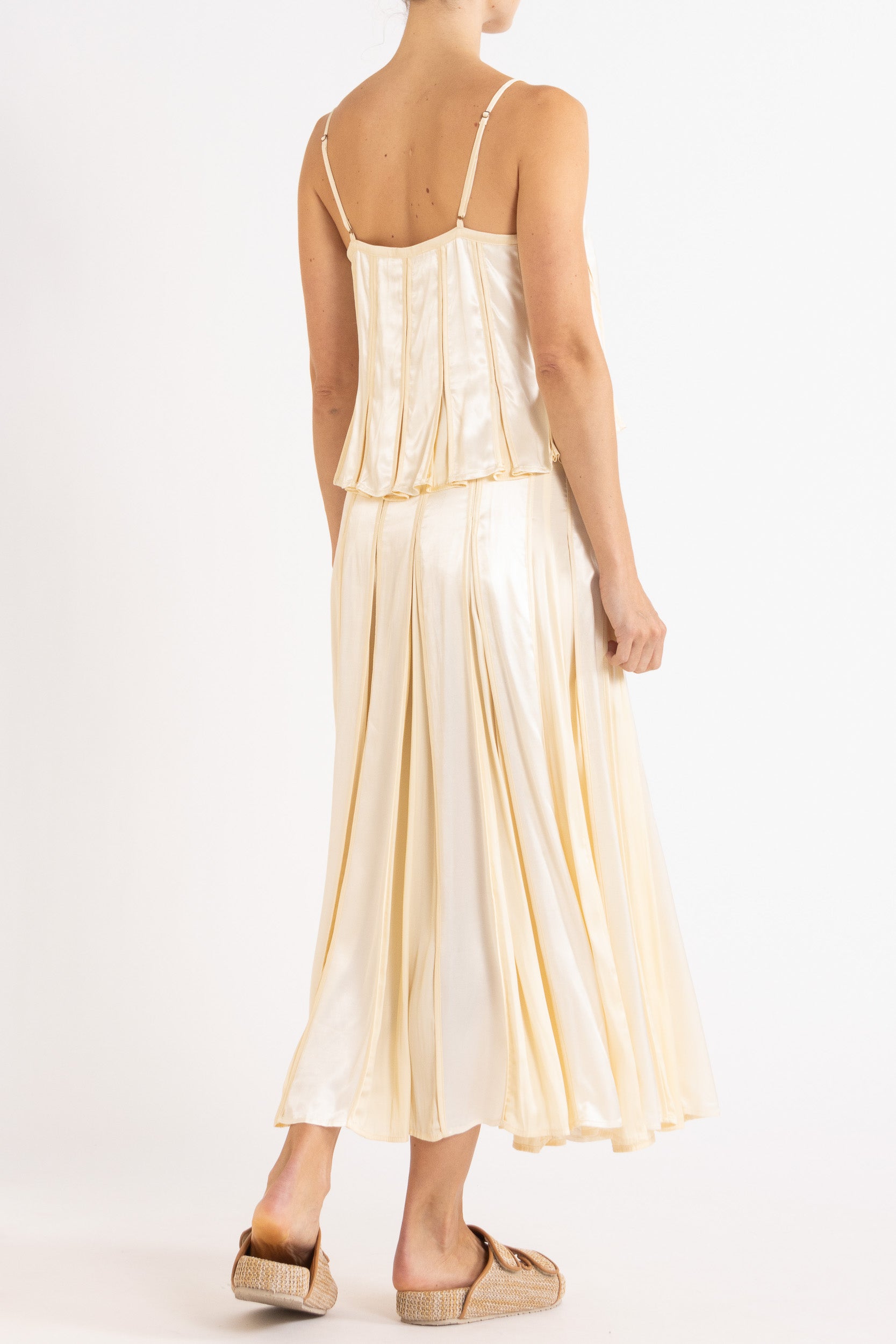 Model wearing cream box pleat camisole & skirt, back-side view