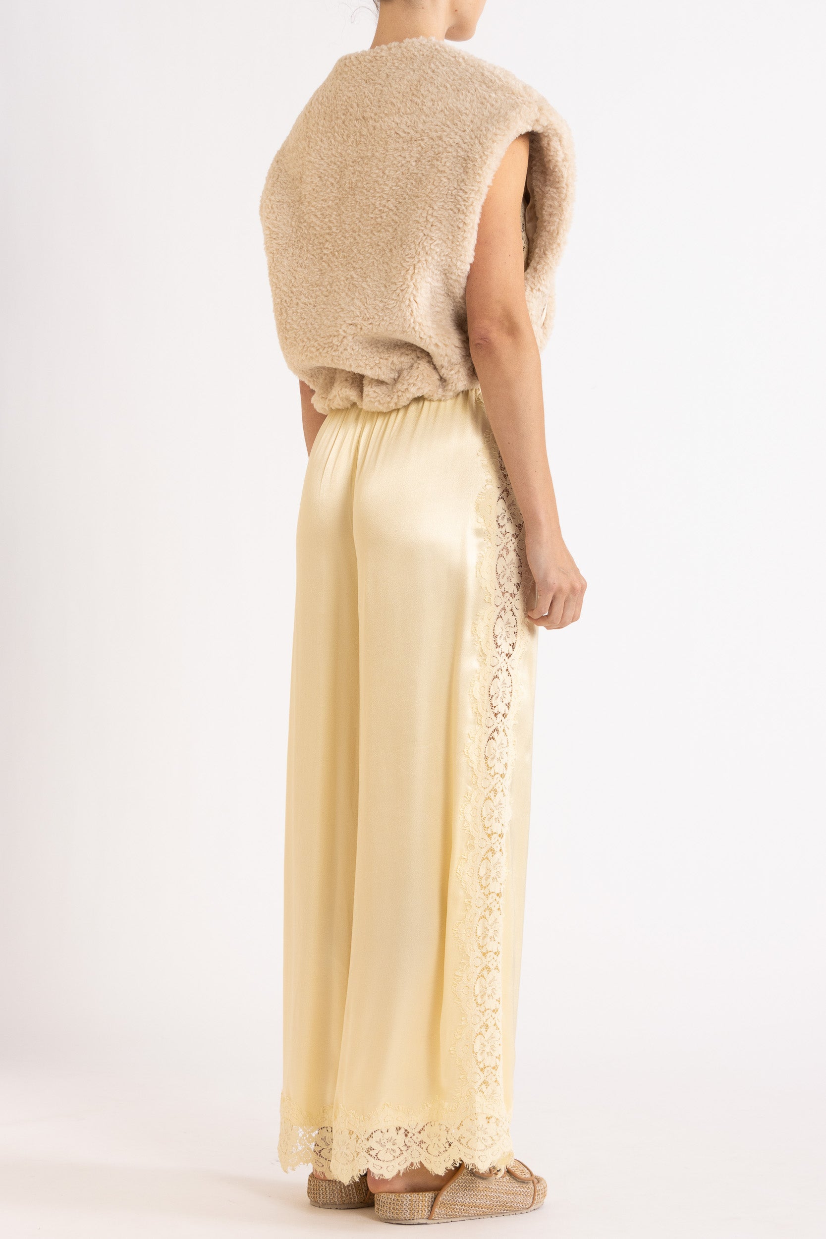 Woman wearing oat colour faux fur zip up vest with vanilla lace-trimmed pants