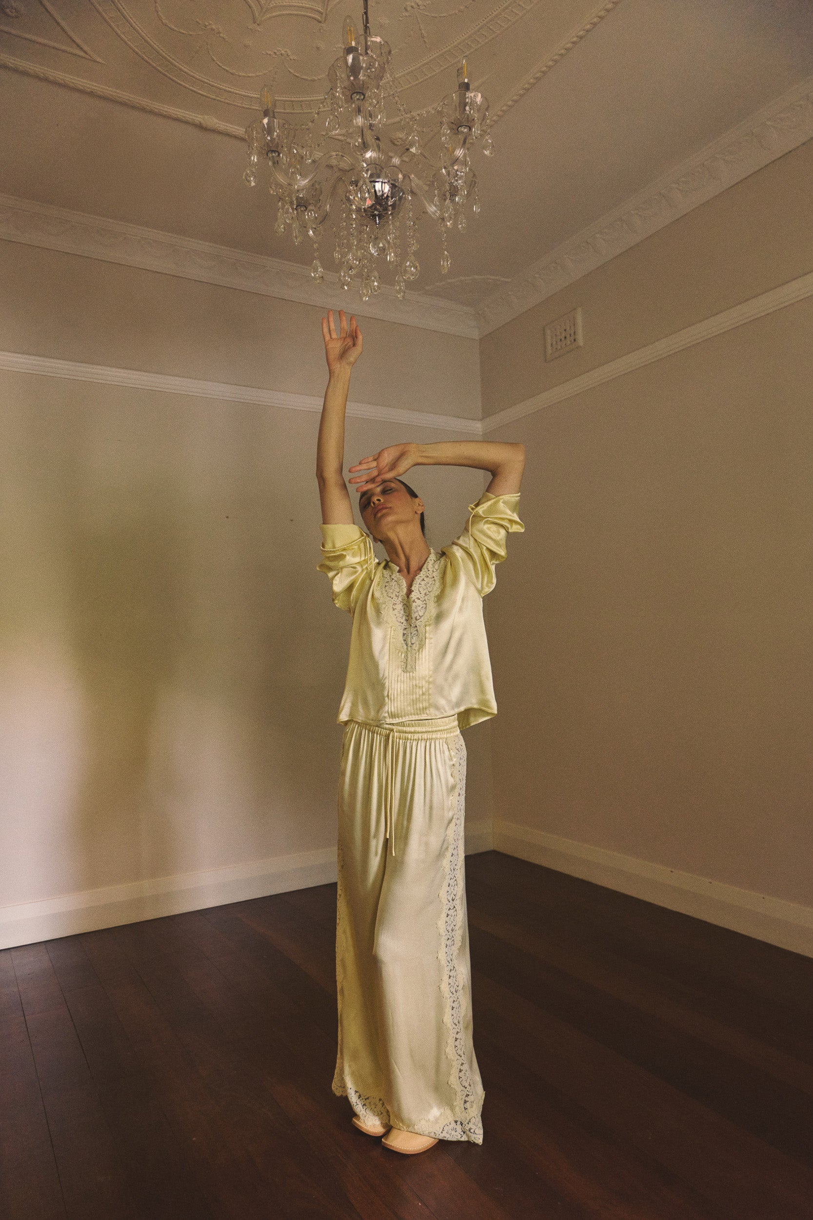 Woman wearing matching vanilla lace-lined top and pant standing on an empty room