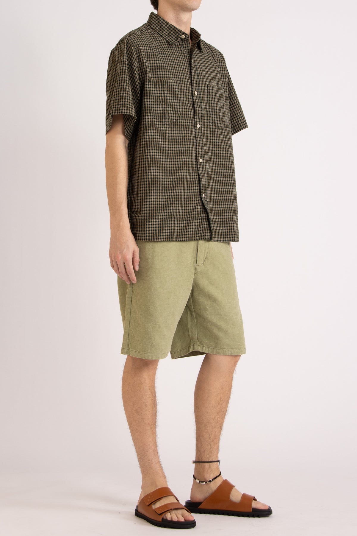 Model wearing a green check cotton shirt and green cotton shorts on a white background, front side view