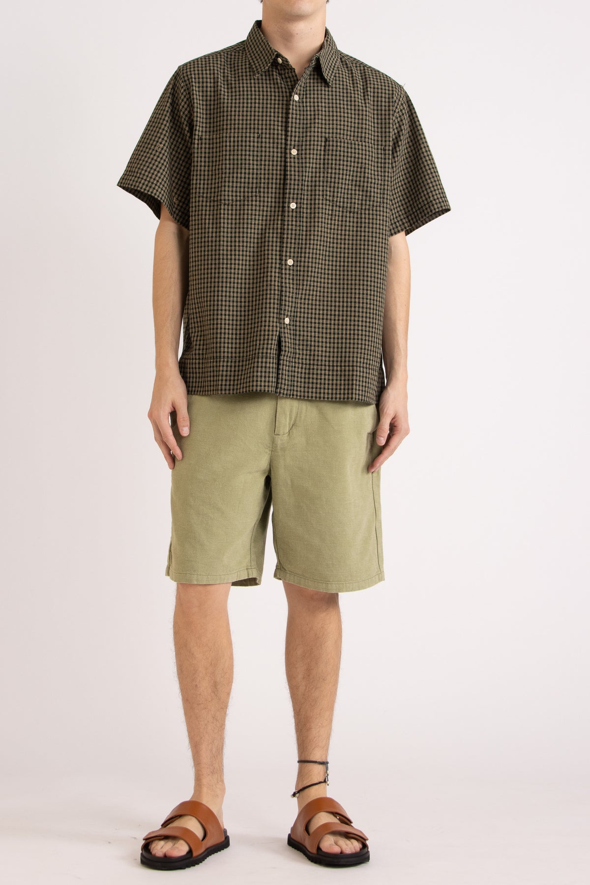 Model wearing a green check cotton shirt and green cotton shorts on a white background, front view