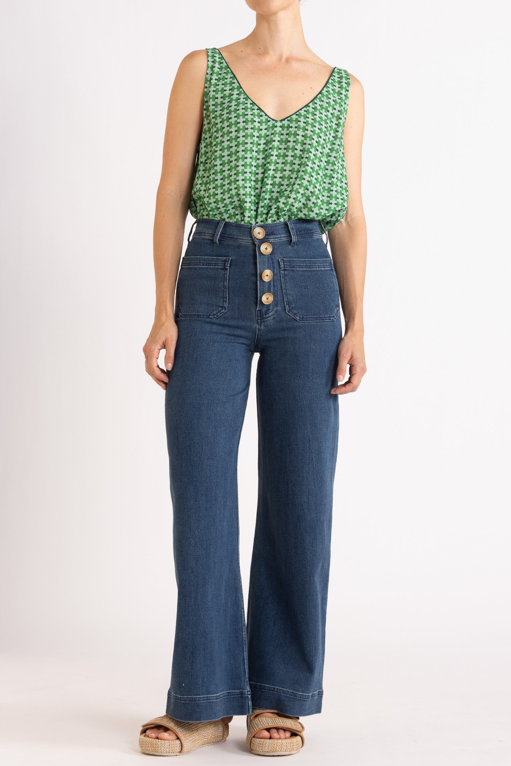 Model wearing green patterned tank top and high-waisted jeans, front view