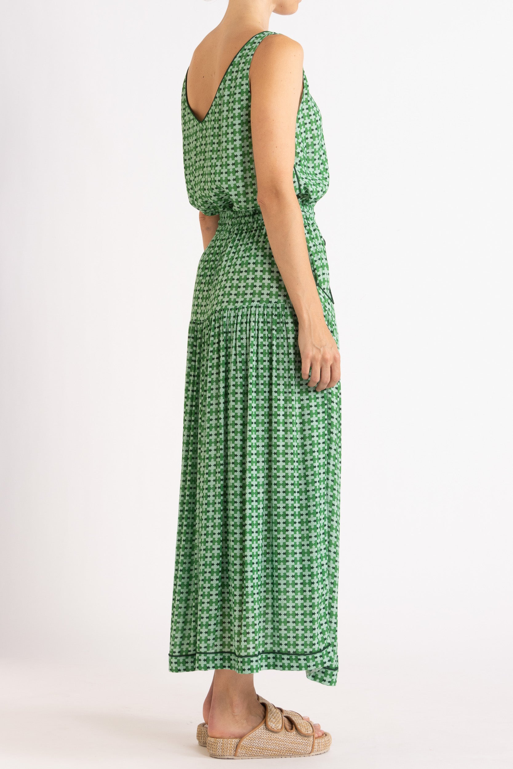 Model wearing green patterned tank top and skirt, side-back view