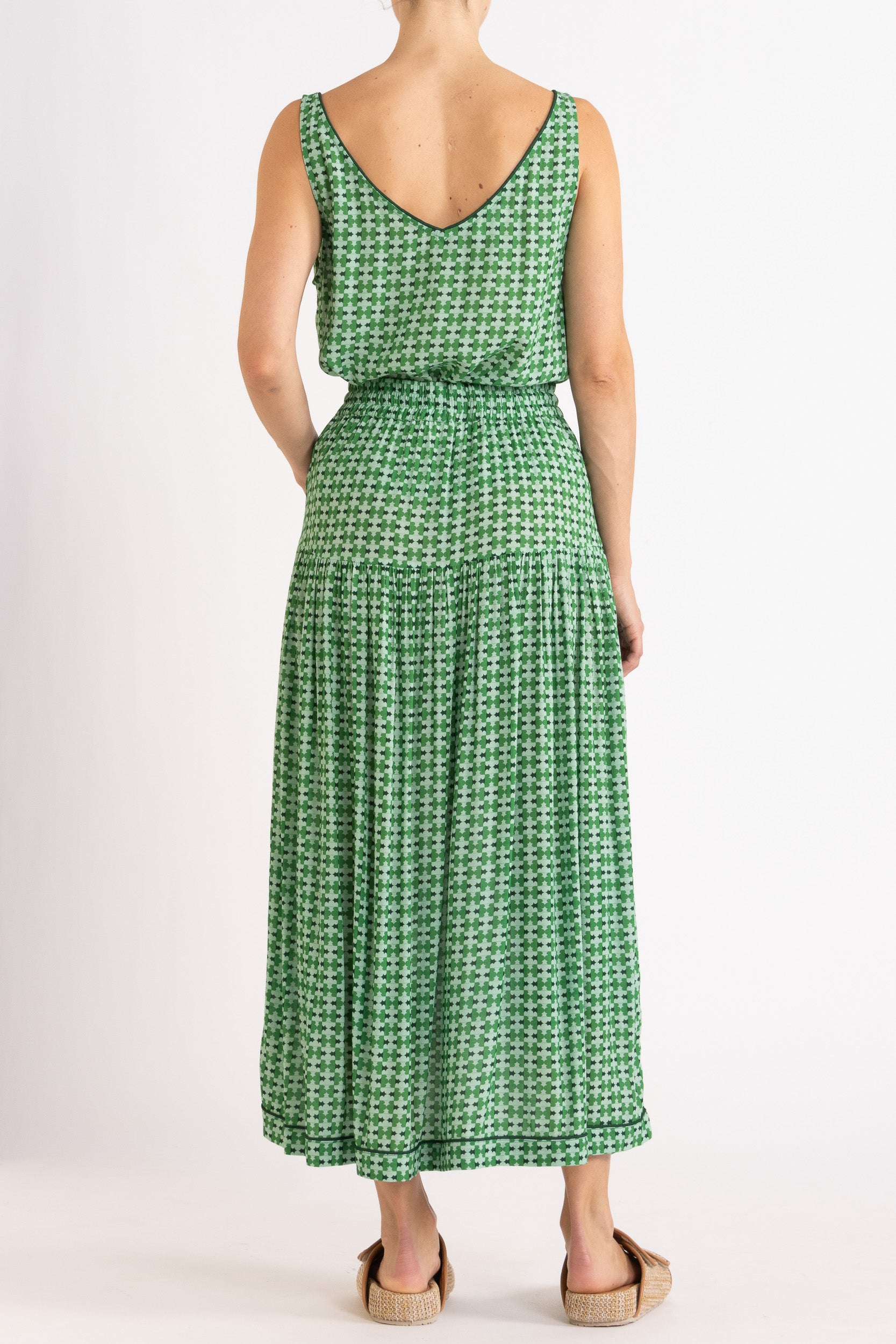 Model wearing green patterned tank top and skirt, back view