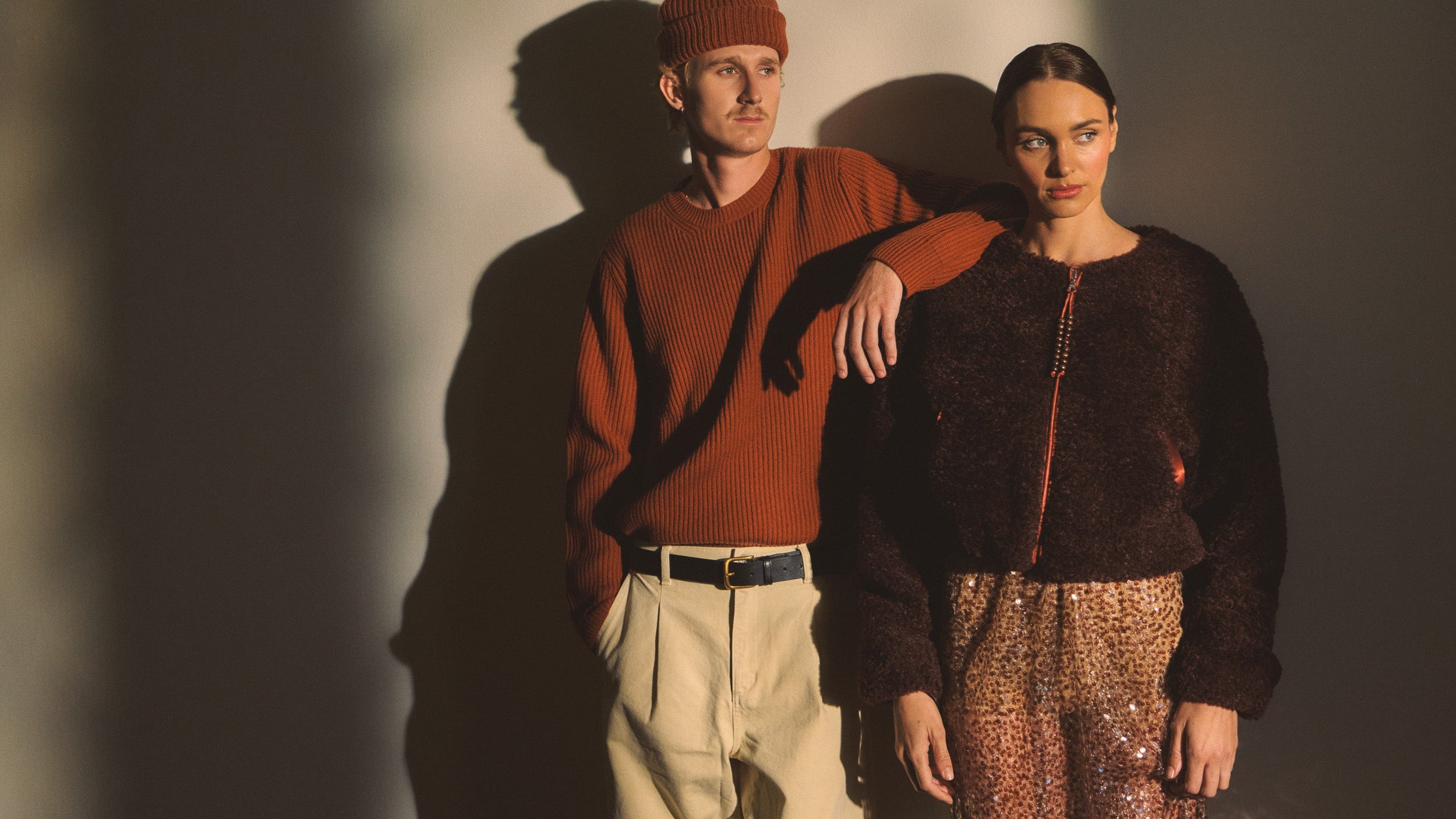 Two people standing close together with a warm color palette against a neutral background