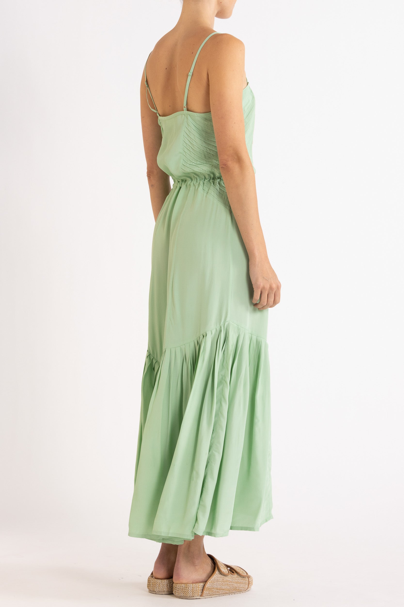 Woman wearing a light green dress with floral embroidery on a white background