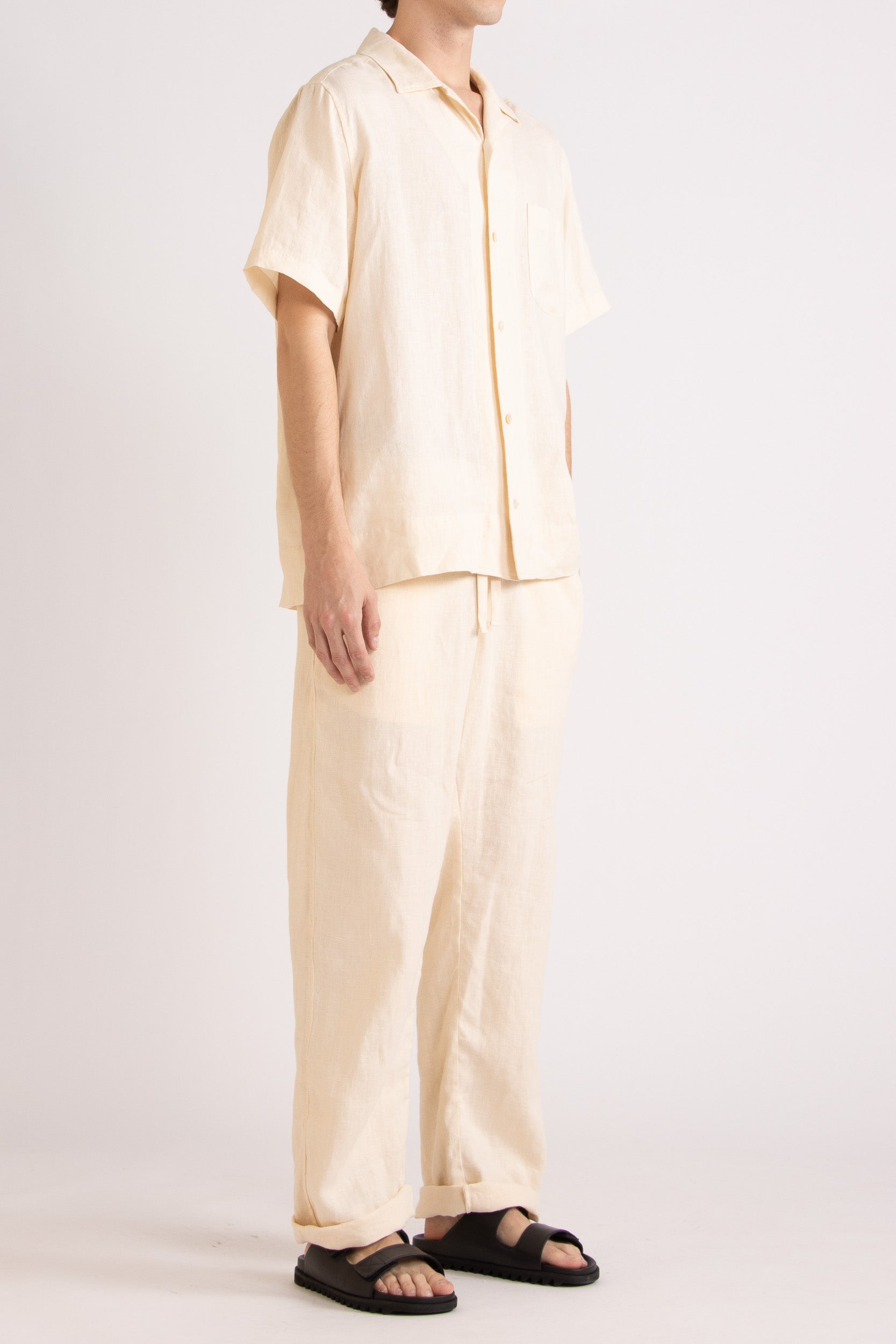 Model wears matching natural linen shirt and pant on plain white background, side view