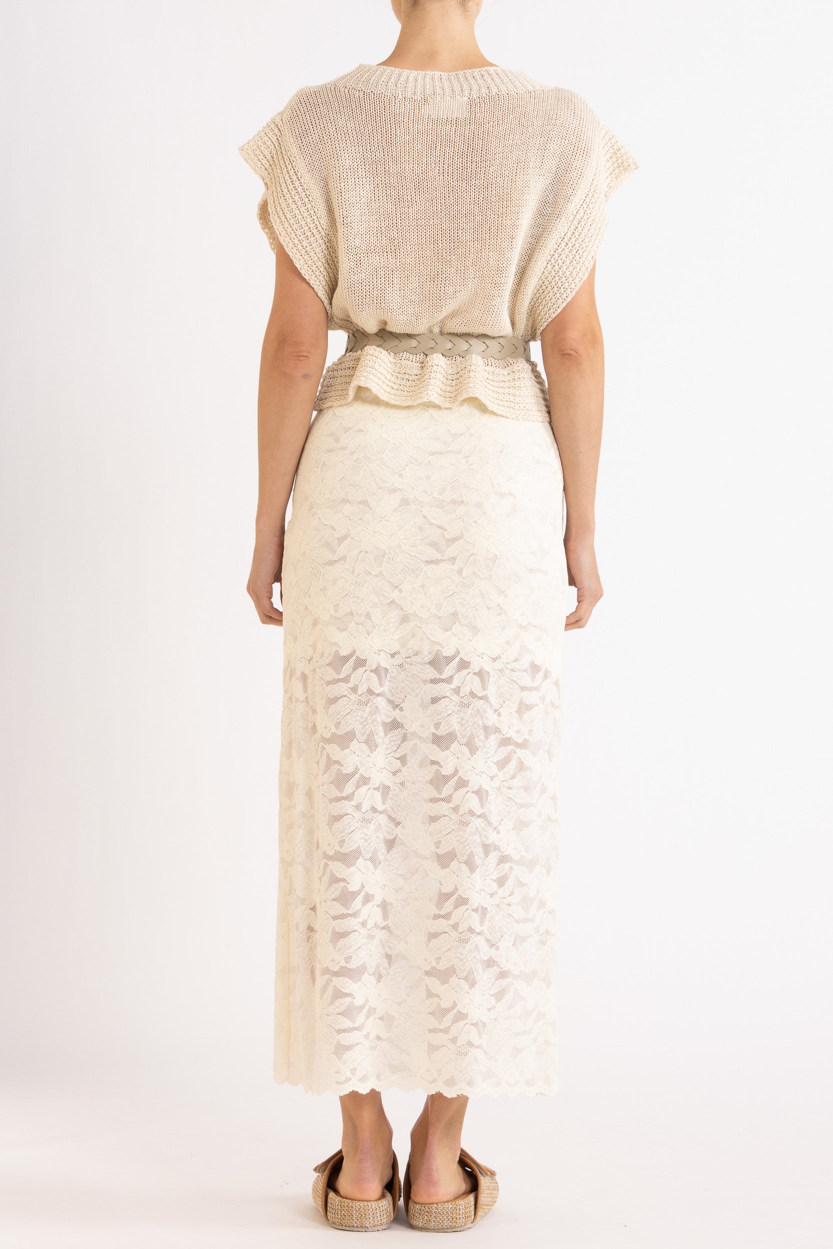 Woman wearing an oat linen vest with a cream braided best and white lace maxi skirt