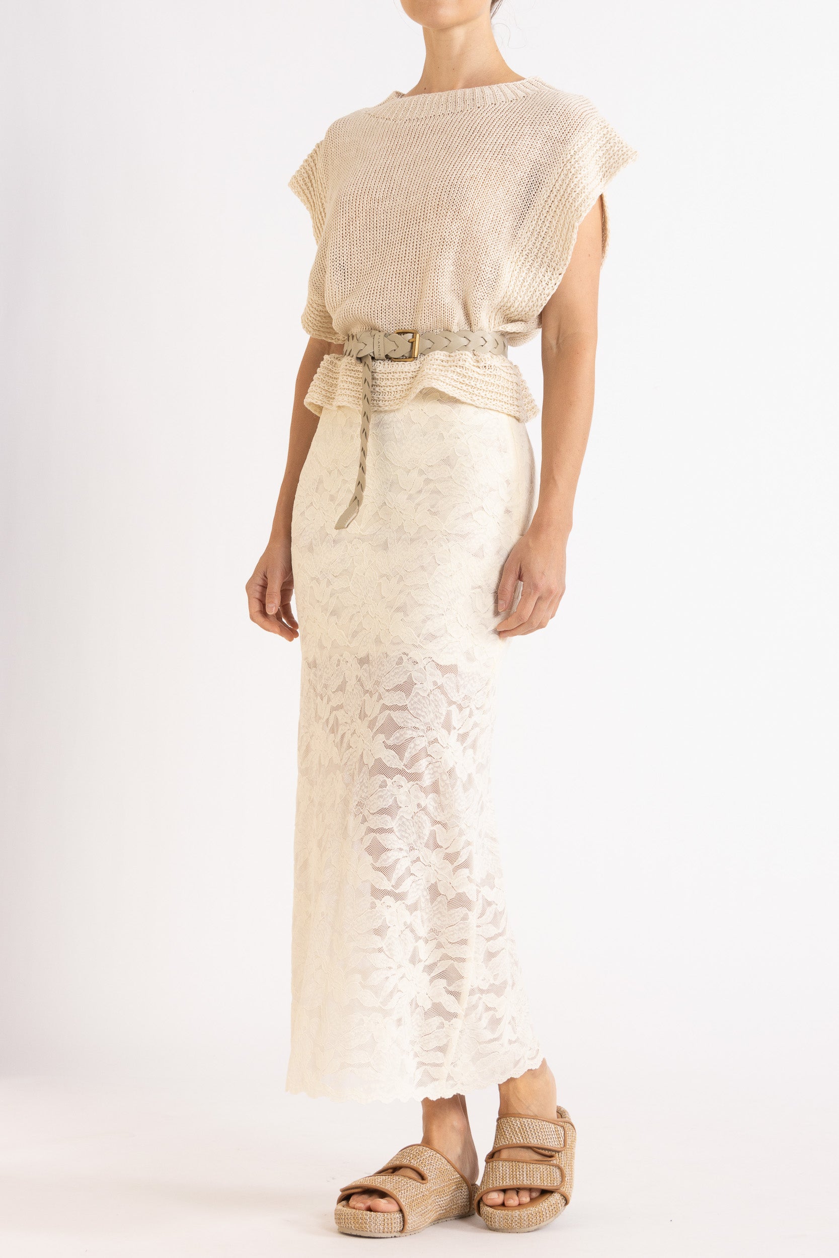 Woman wearing an oat linen vest with a cream braided best and white lace maxi skirt