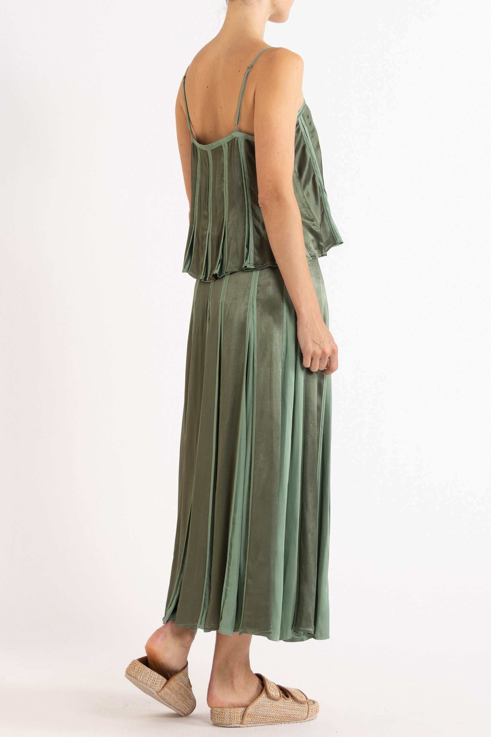 Model wearing cream box pleat camisole & skirt, side-back view