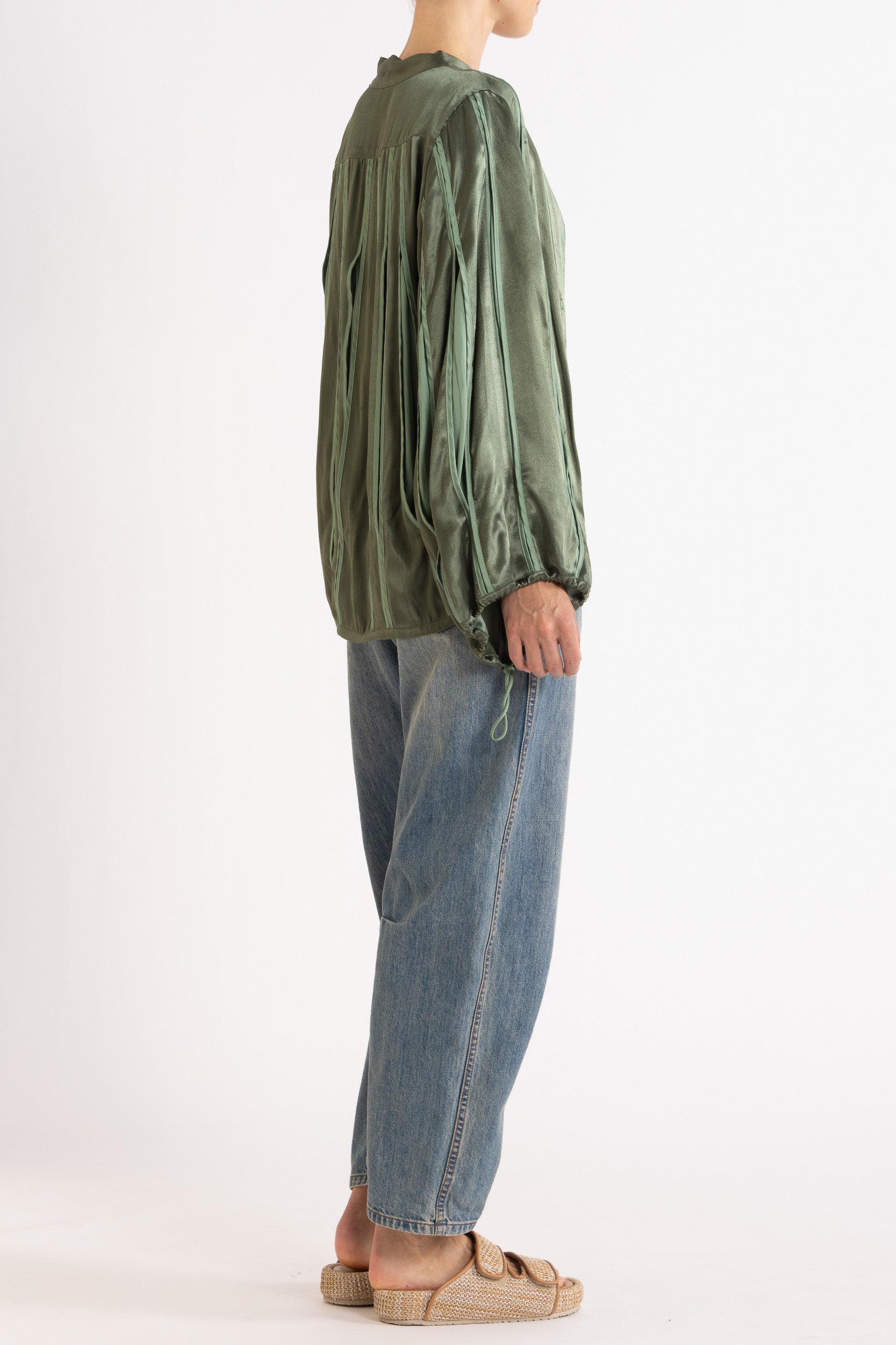 Model wearing cream box pleat camisole & skirt, side-back view