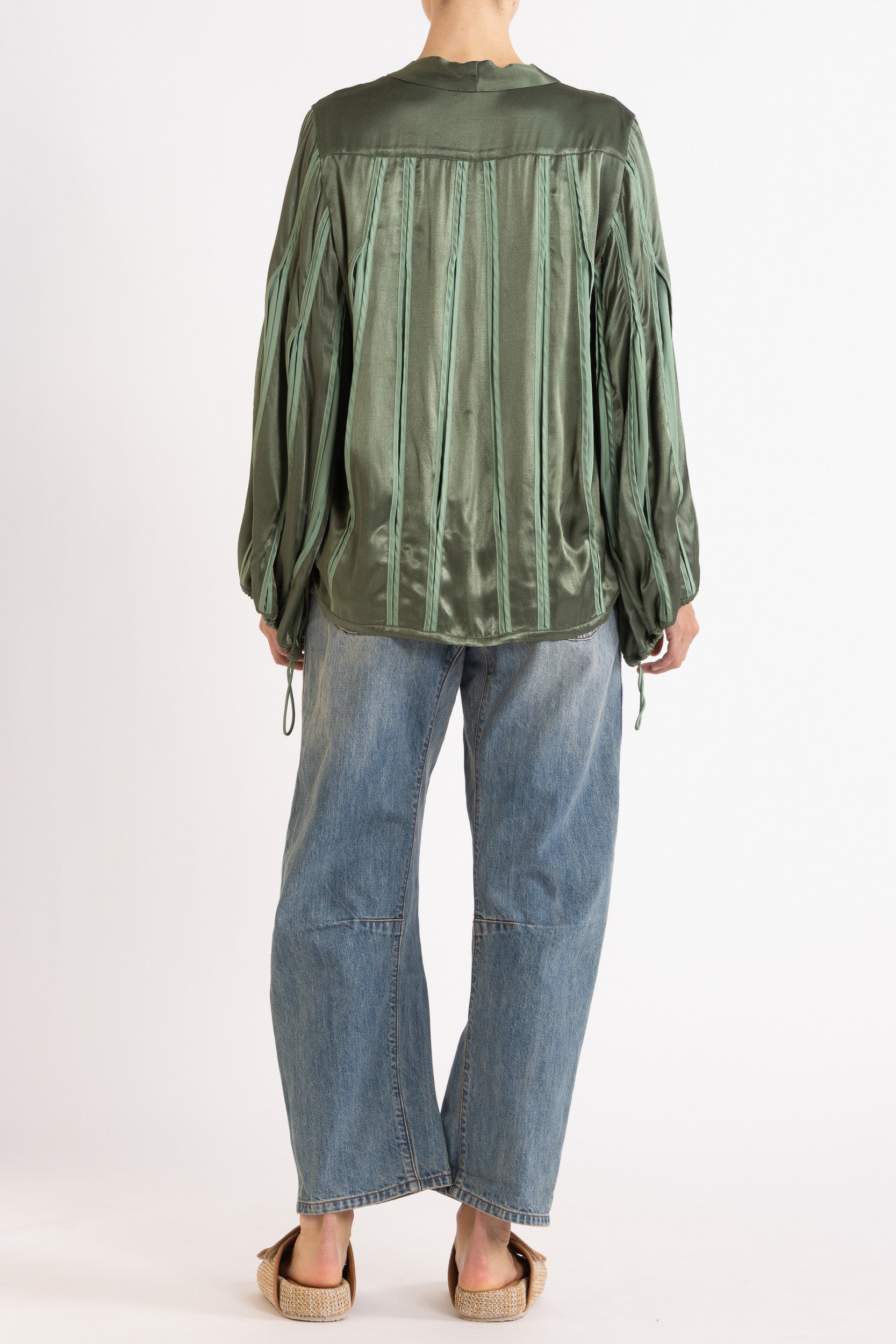 Model wearing green box pleat jacket, blue lace camisole & denim jean, back view