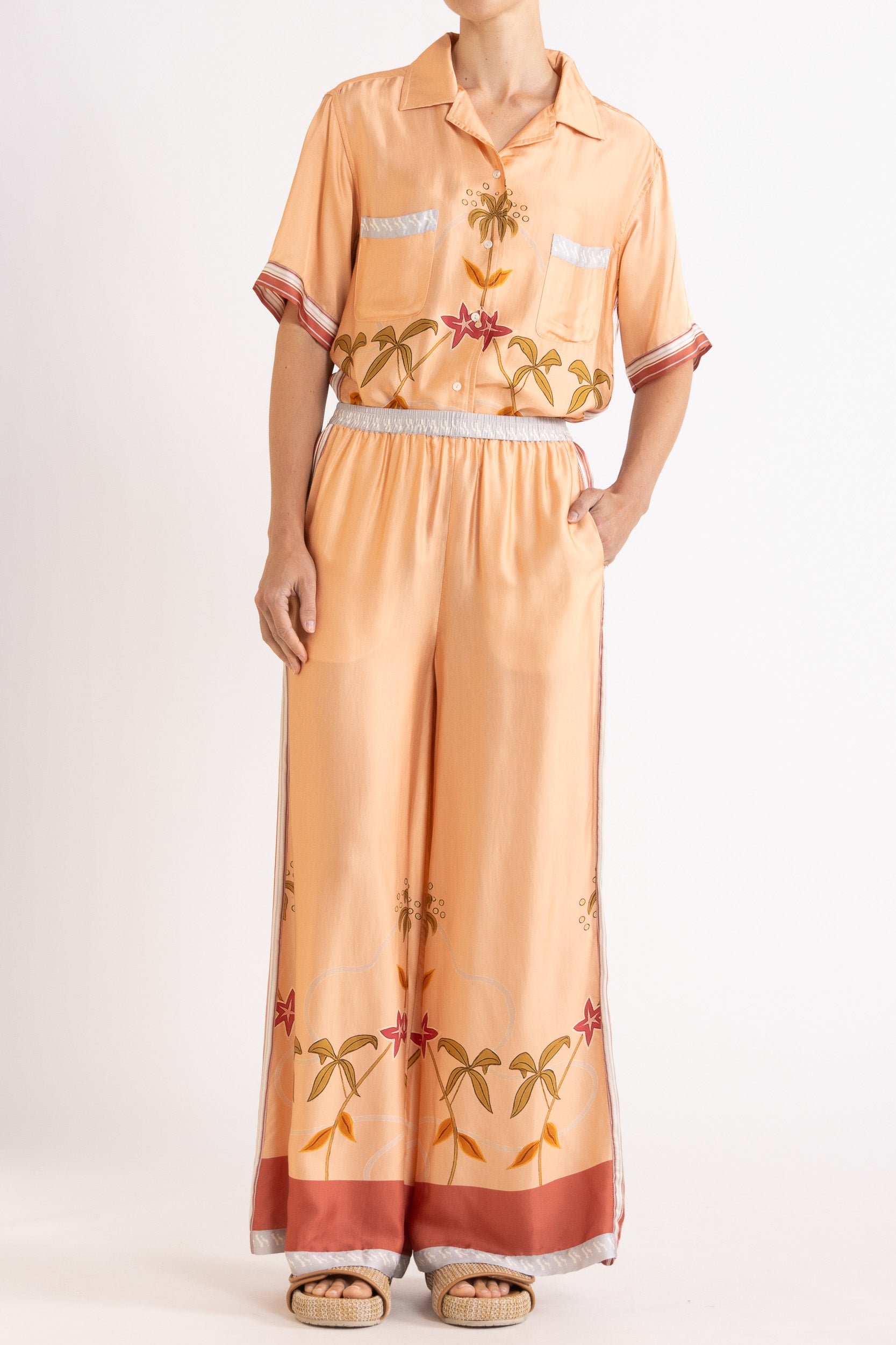 Woman wearing a matching peach short sleeve shirt and pants featuring floral patterns on a white background